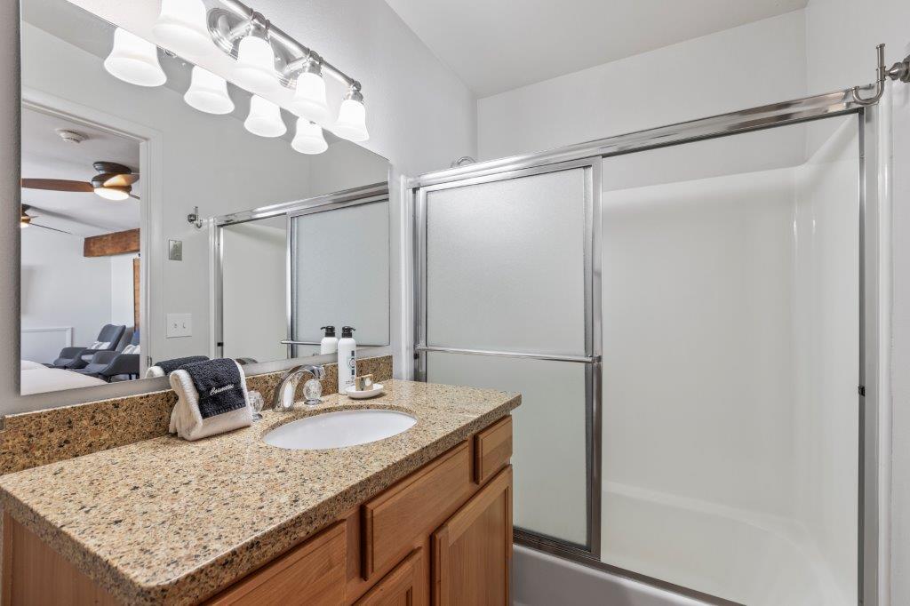 The shared bathroom has a single sink vanity and a bathtub and shower combination.