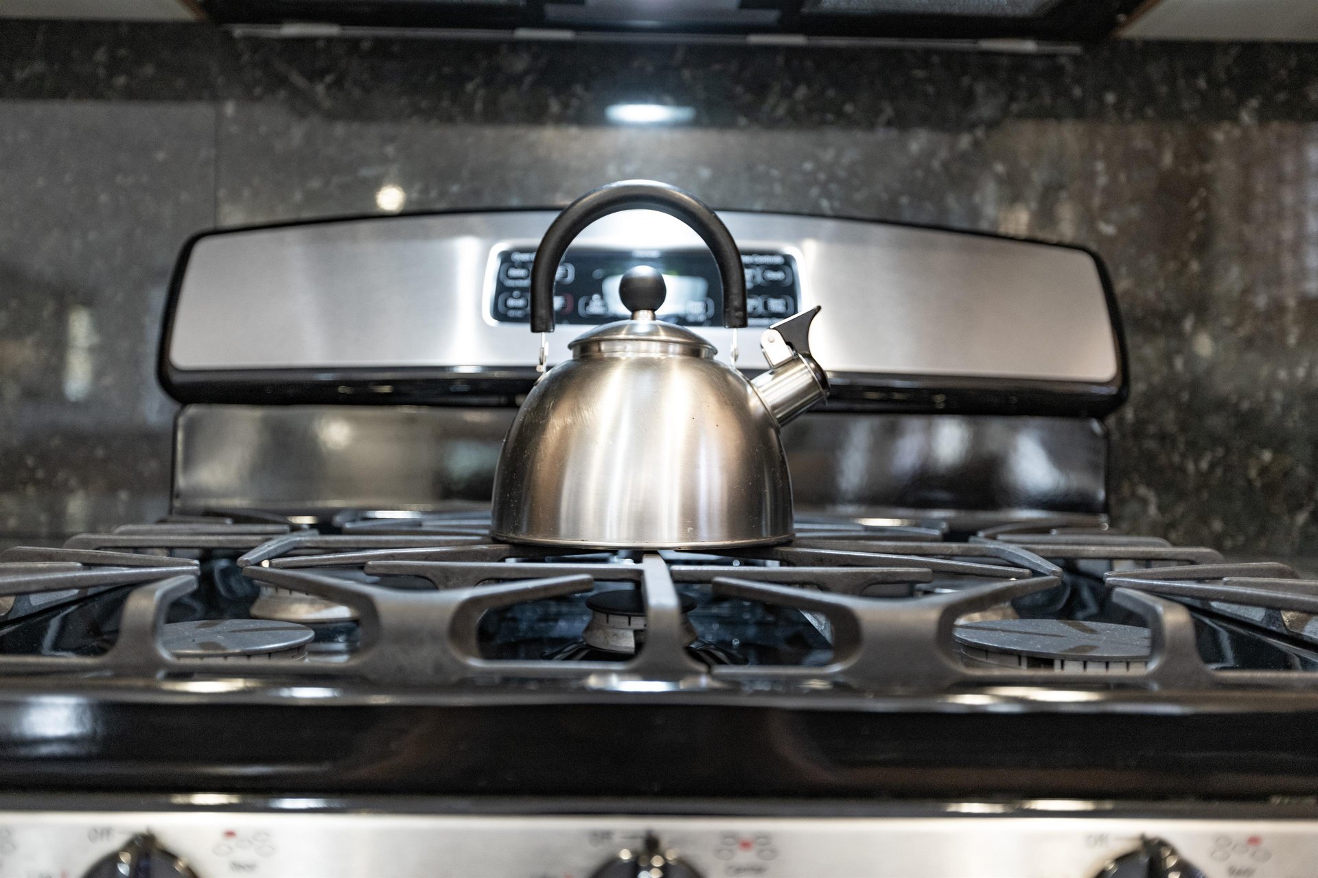 The kitchen has a stainless steel ovenrange and teapot.