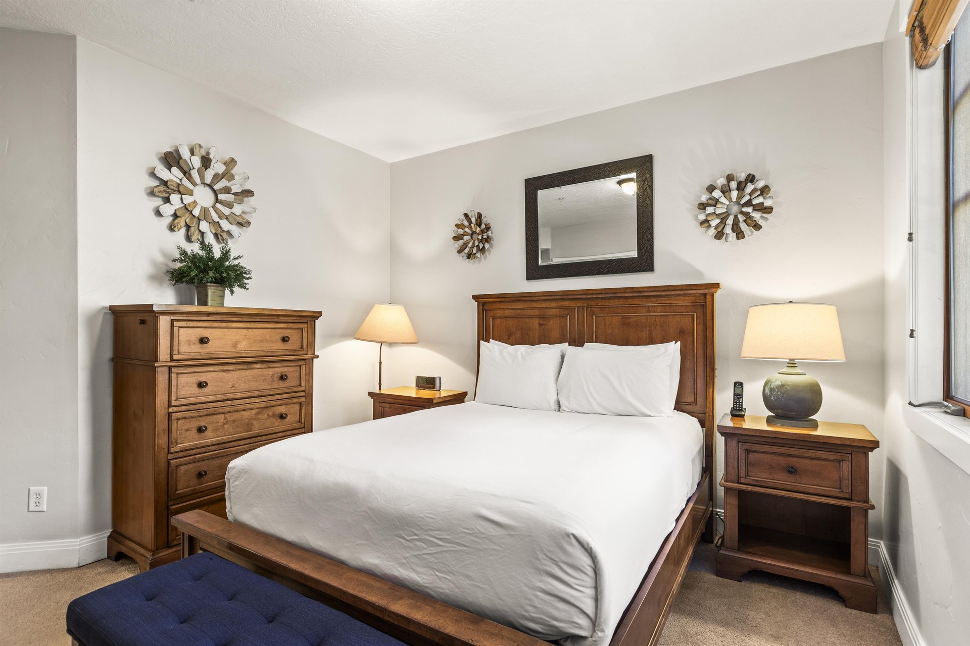 The third bedroom has a queen size bed and wood furniture.
