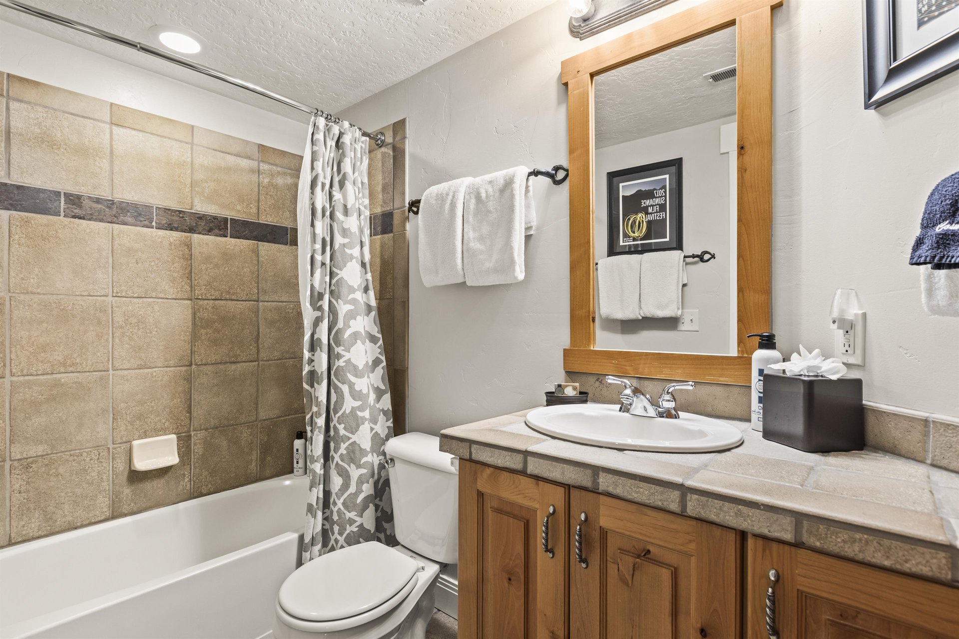 The shared bathroom has a bathtub and shower combination and single sink vanity.