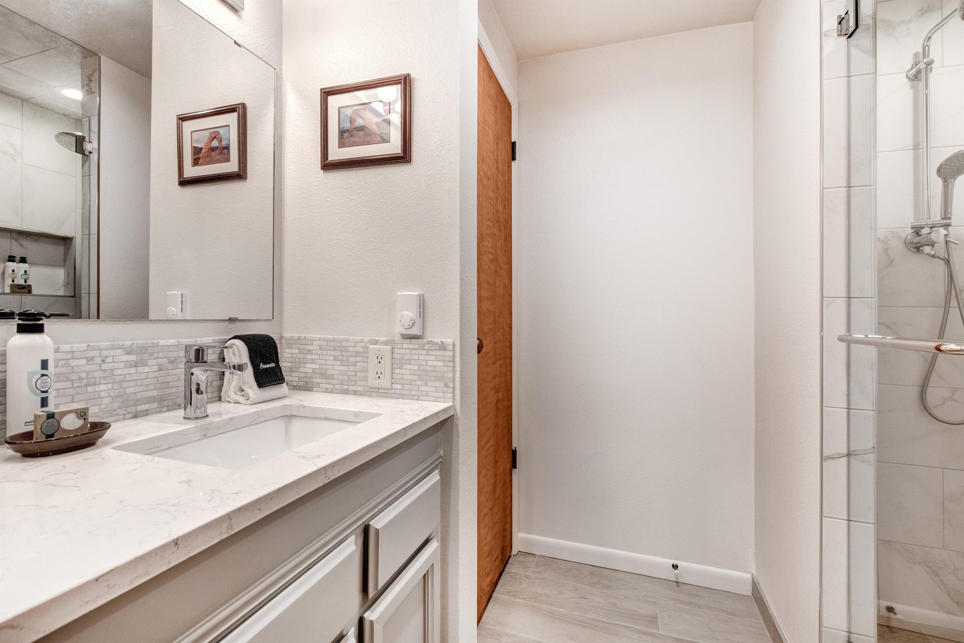 The en suite bathroom has a spacious single sink vanity and large mirror.