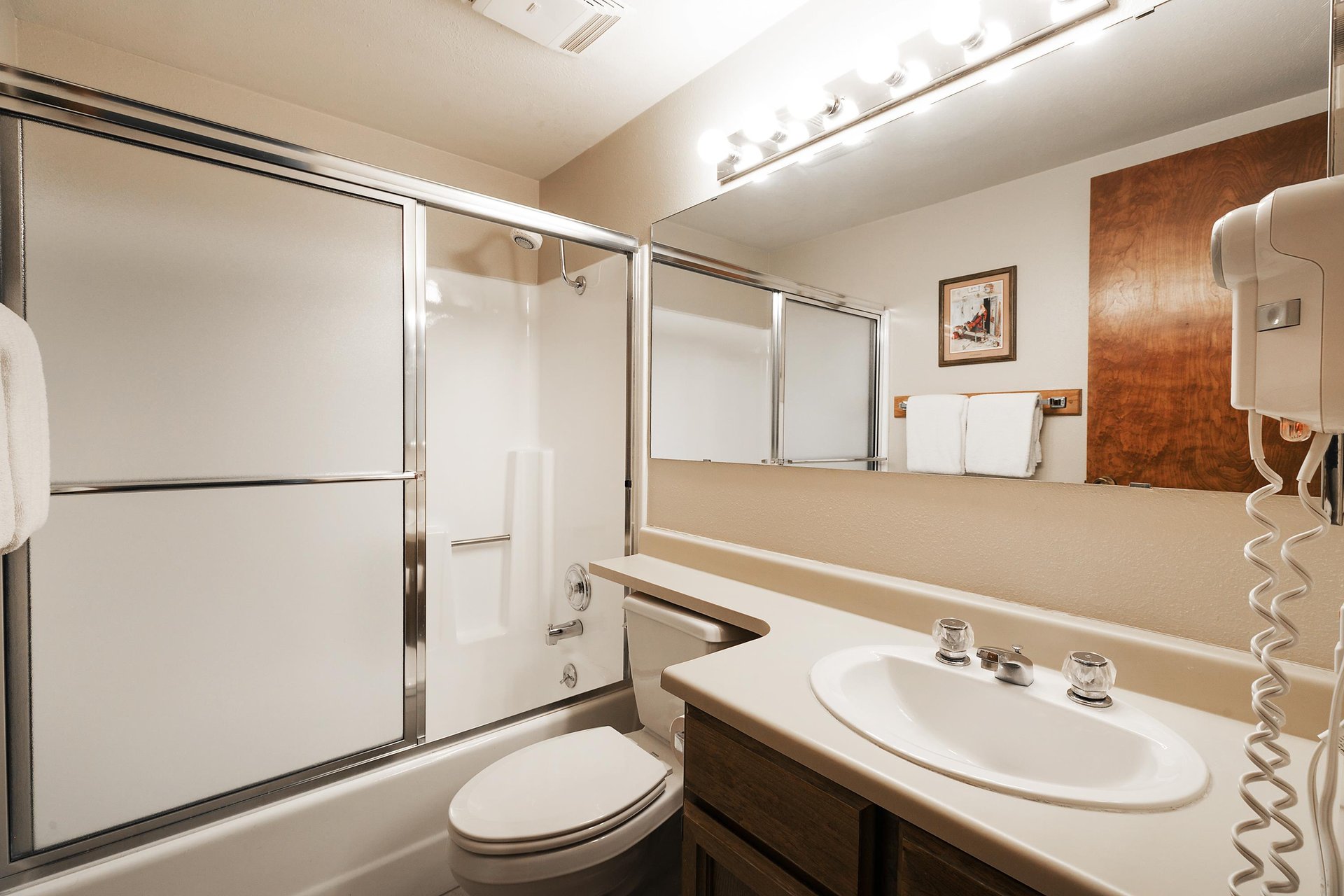 Shared guest bathroom features a bathtubshower combination, large mirror and white countertops