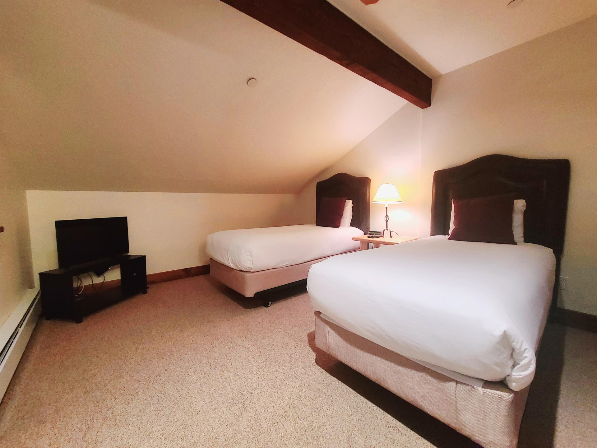 Fifth bedroom includes two comfortable twin sized beds with white linen and flat screen TV