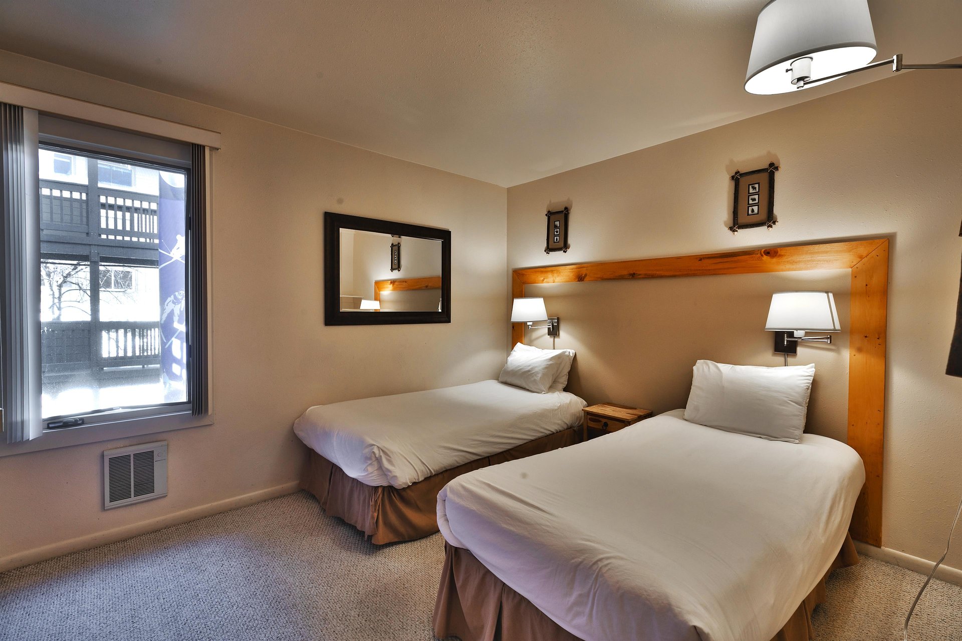 Guest bedroom includes two comfortable twinsized beds, large mirror and wall mounted lamps above the beds