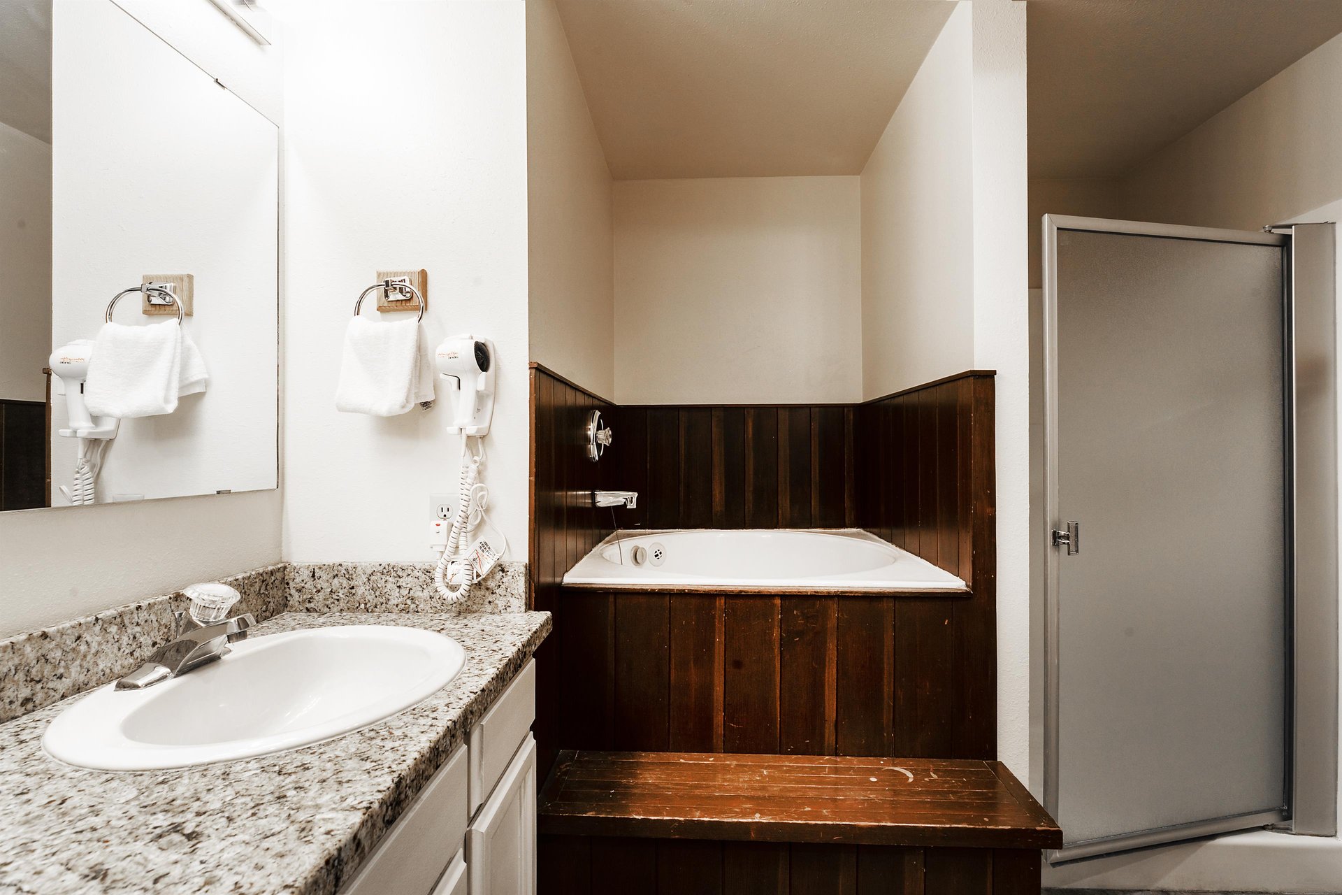 The shared guest bathroom includes white cabinets, granite countertops, a deep soaking tub and walkin shower