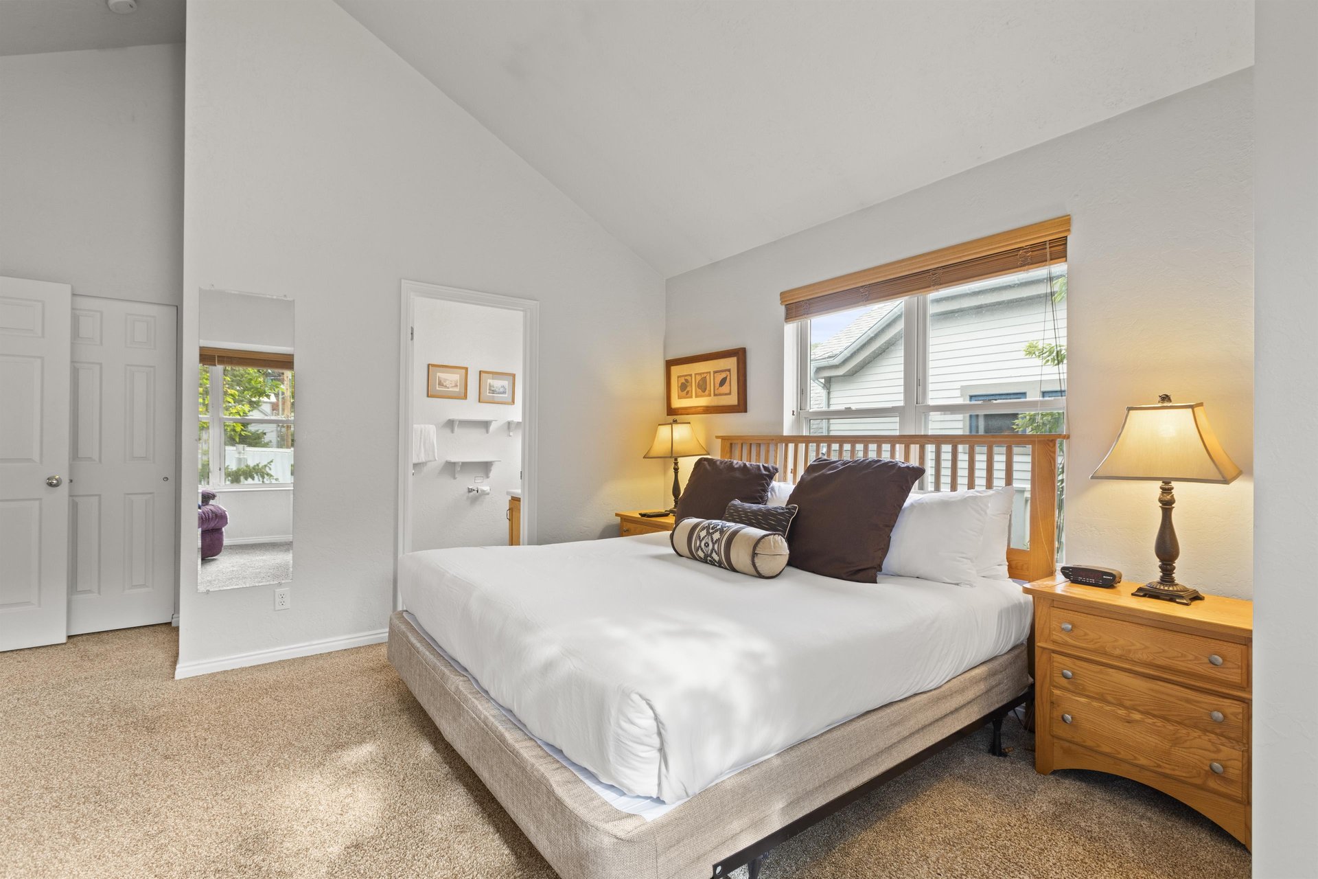 The bedroom has a king size bed with crisp white bedding and large throw pillows.