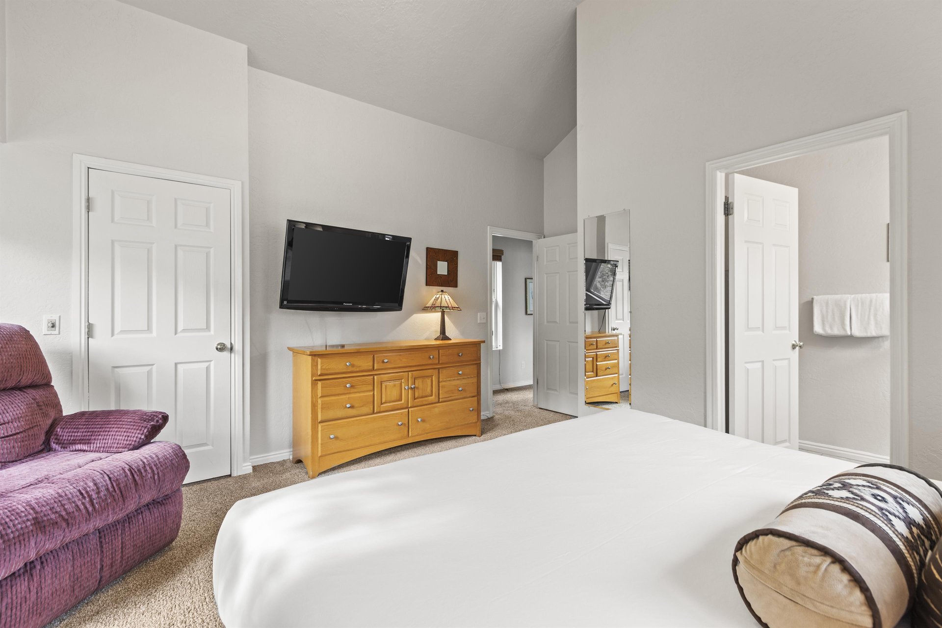 The bedroom has a king size bed, wooden dresser, and flat screen TV.