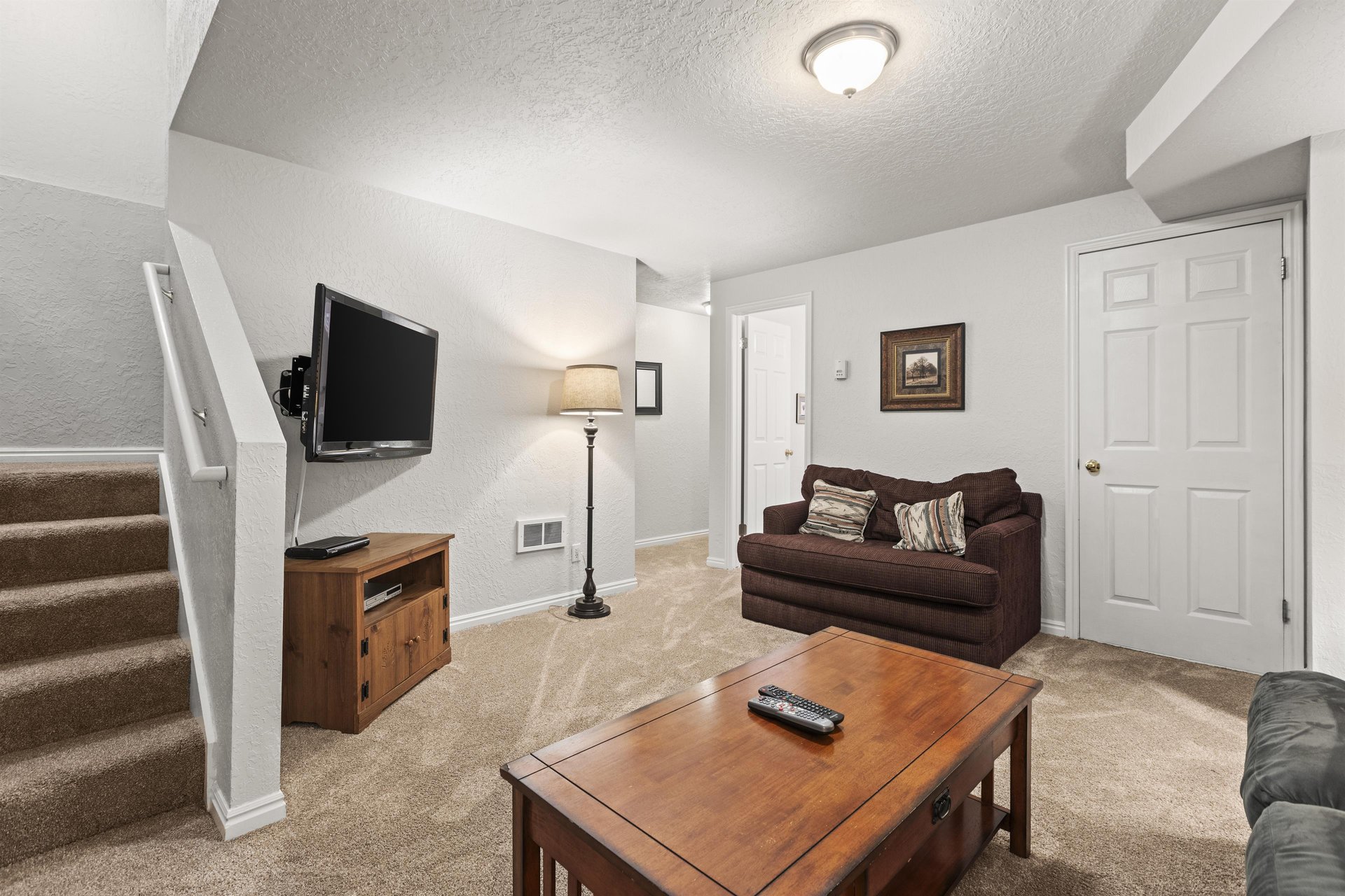 The third living area with comfortable seating, wood furniture, and flat screen TV.