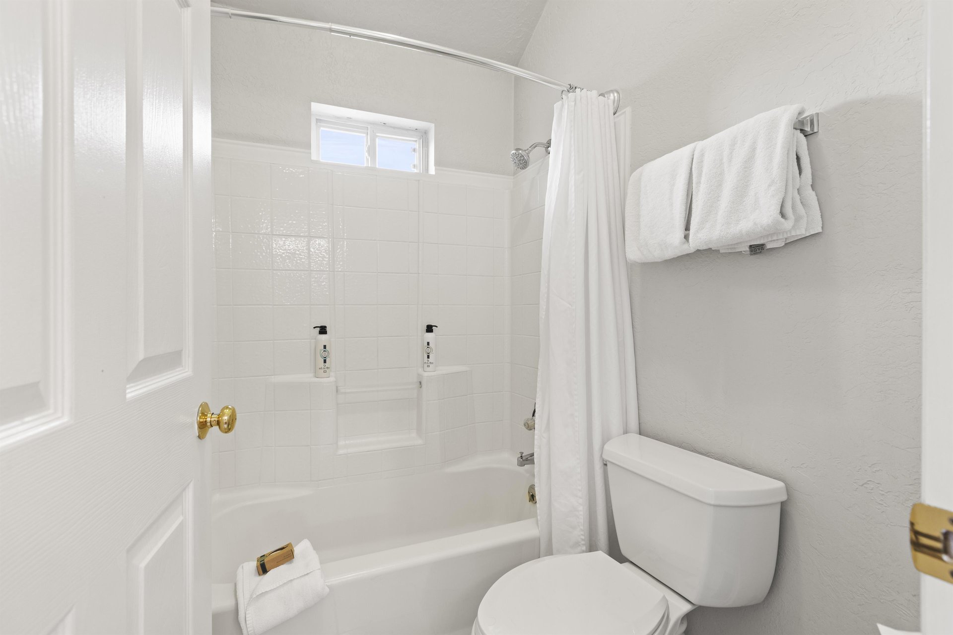 The bathroom in all white with a bathtub and shower combination.