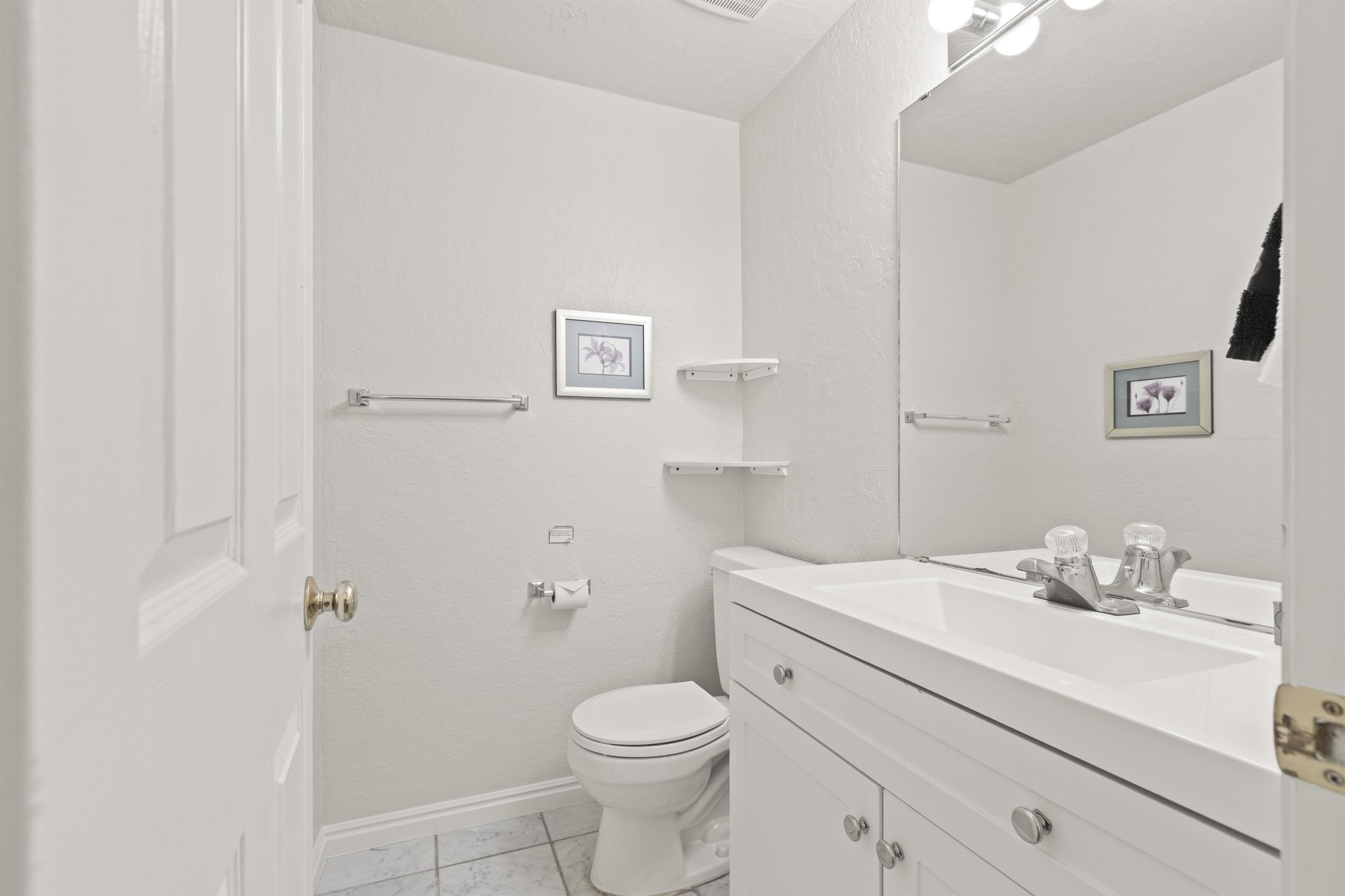 The bathroom in all white with a single sink vanity.