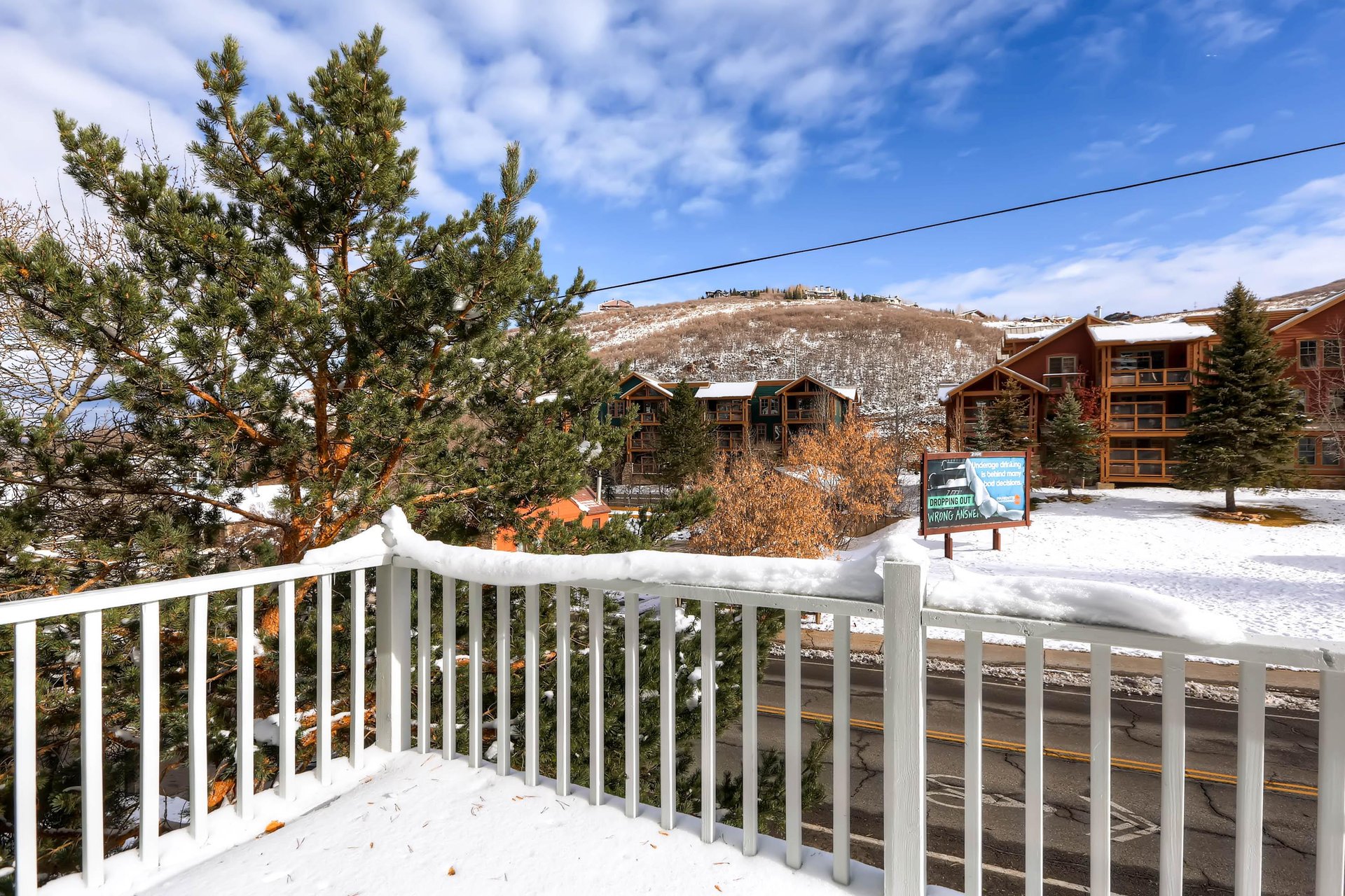 Upper level balcony with scenic view of snowy pines and blue skies