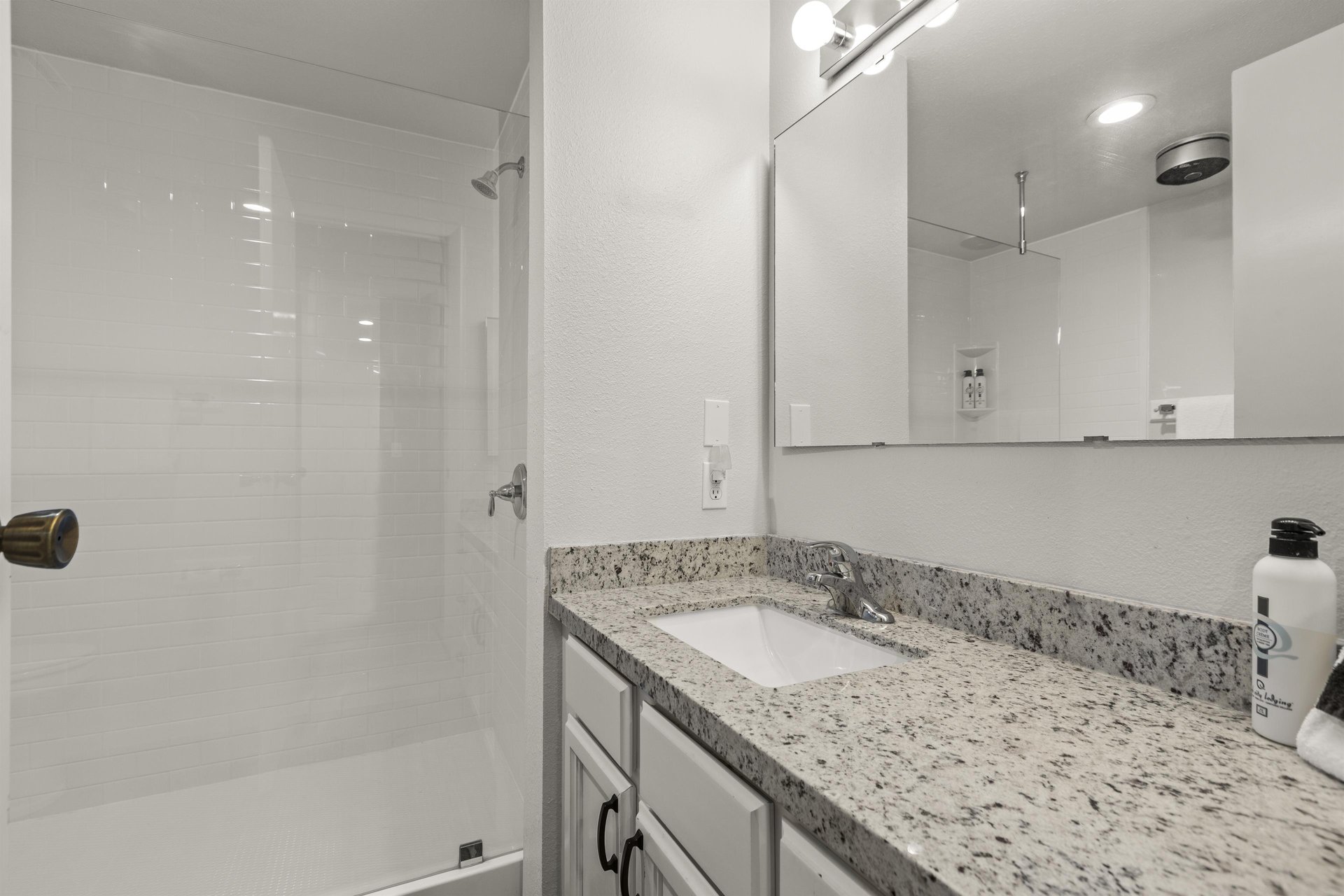The shared bathroom offers a walkin shower and single sink vanity.