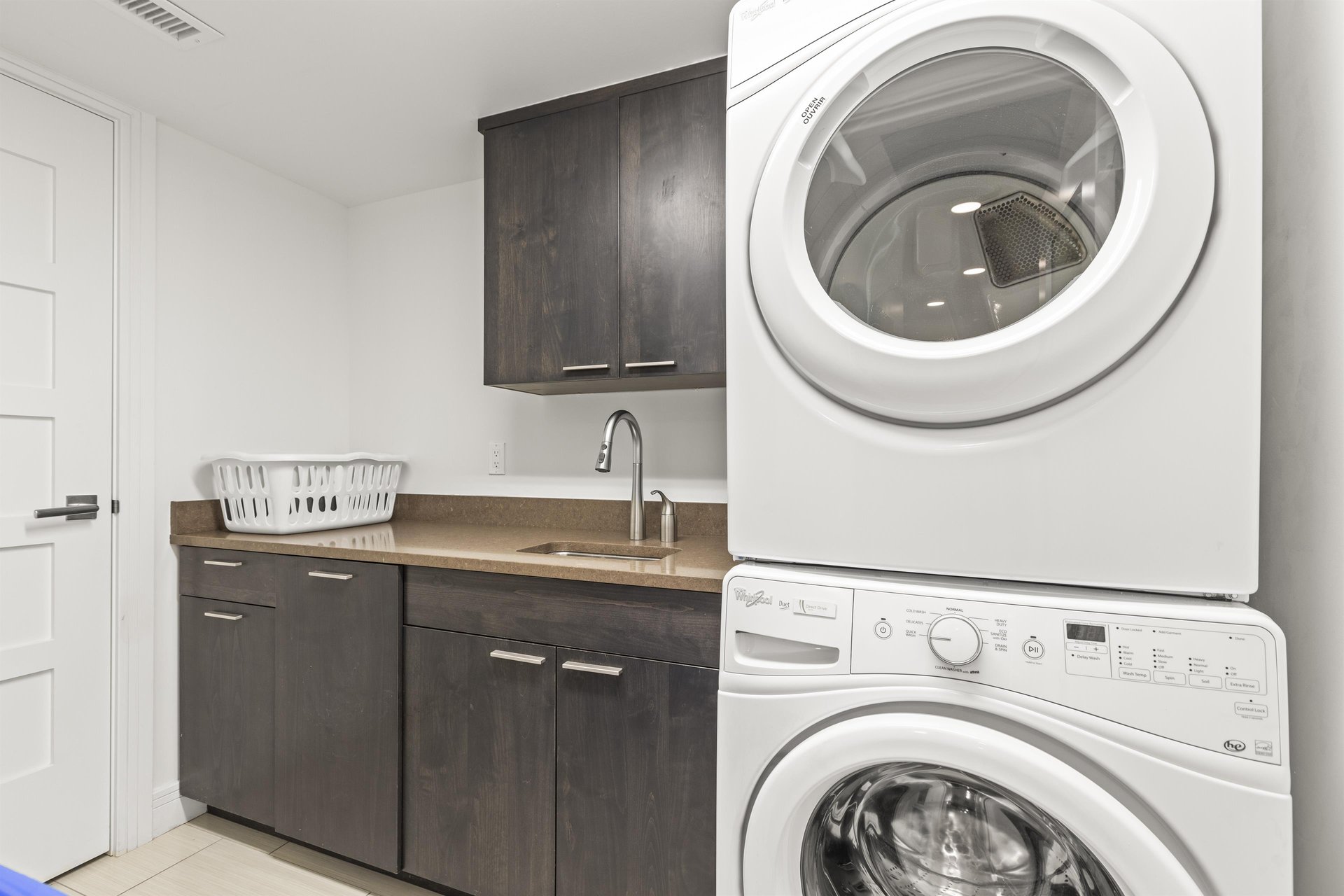 The private stackable washer and dryer in a laundry room with folding area.