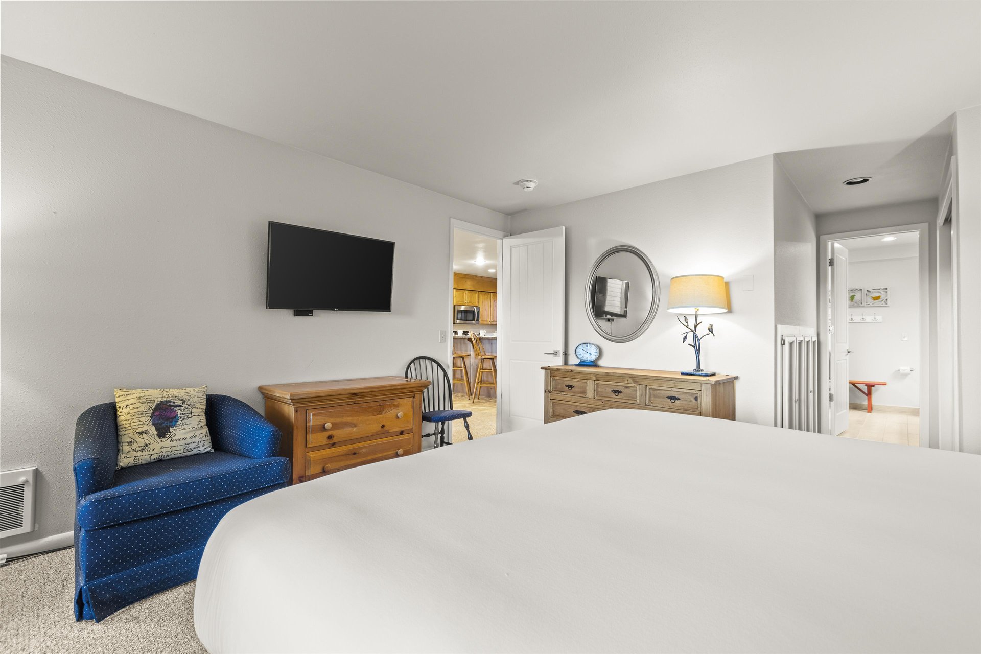 The main suite with a kingsize bed, wood dresser, and flat screen TV.