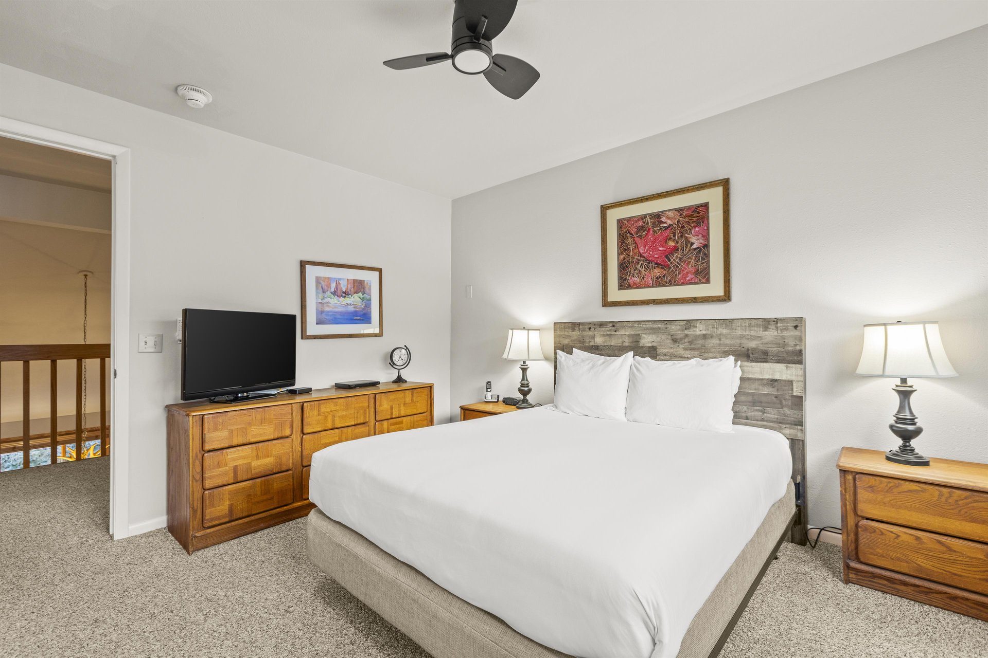 The bedroom with a queen size bed, wood dresser, and flat screen TV.