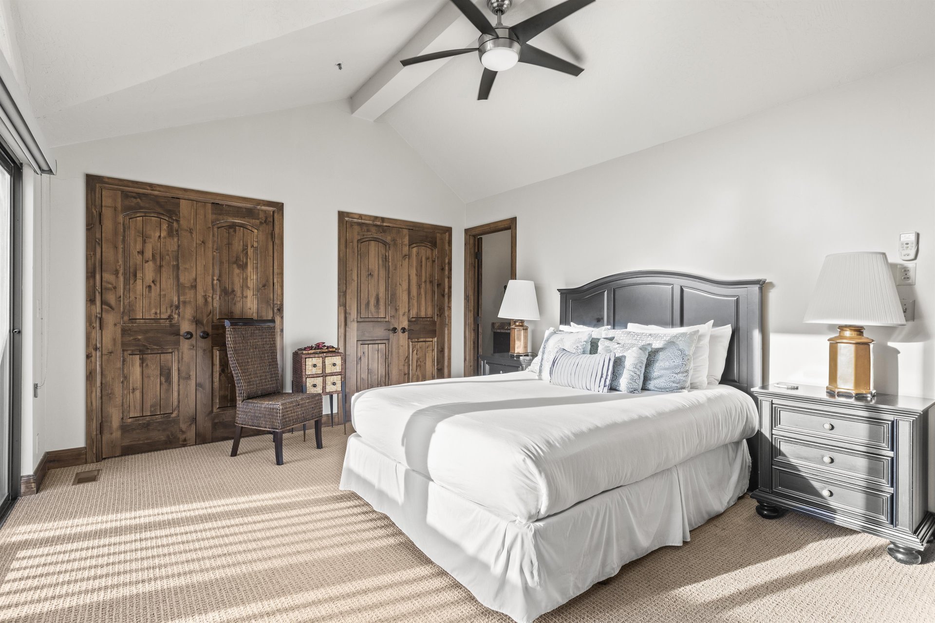 The main suite has a queensize bed, tan carpet, and wooden closet doors.