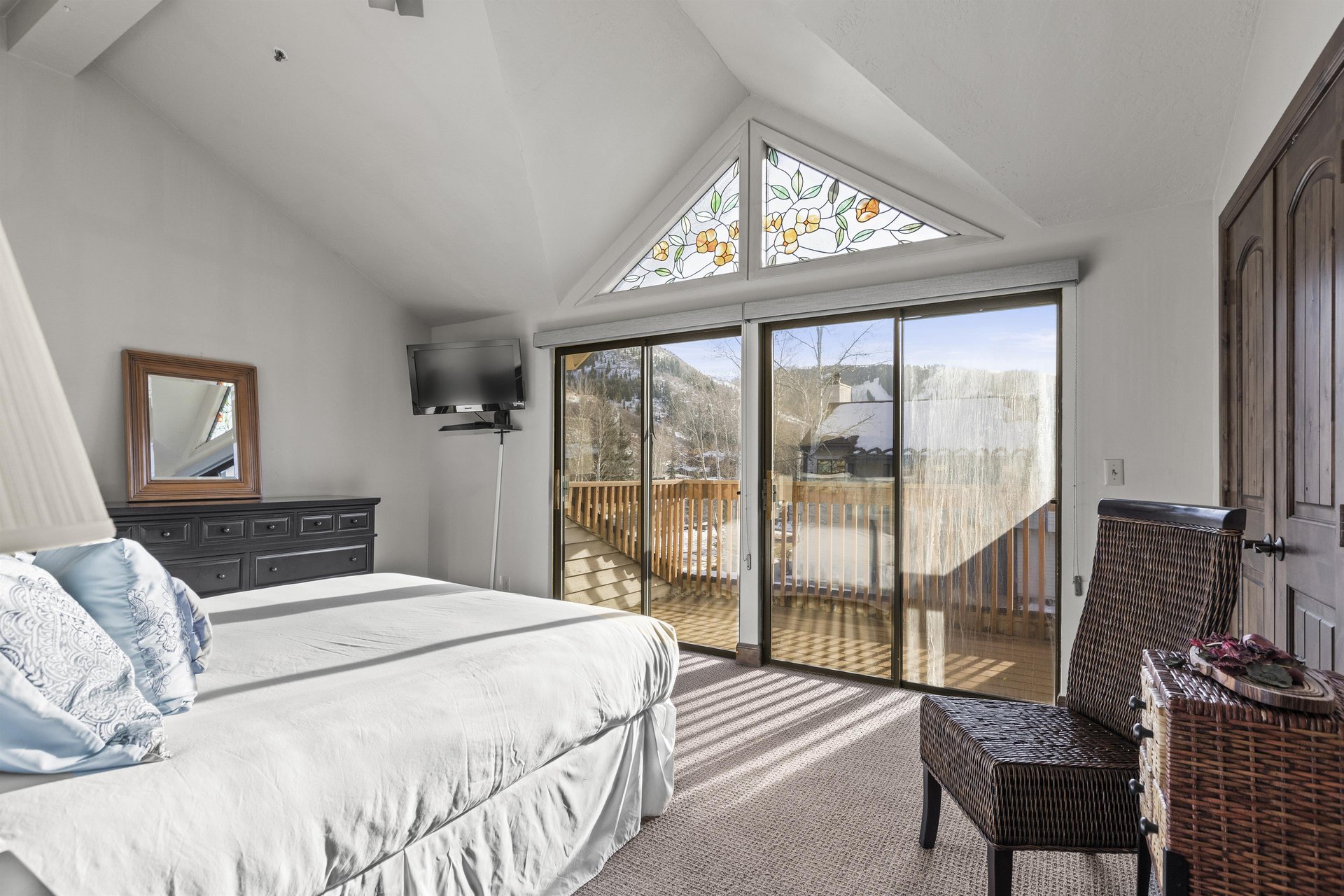The main suite has a queensize bed, flatscreen TV, and large sliding glass doors with mountain views.
