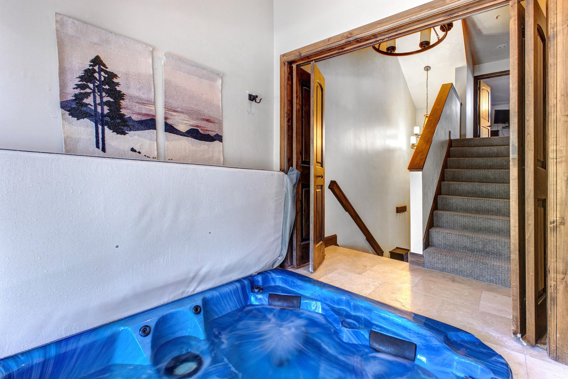 Queen Esther 2425s indoor hot tub with modern landscape art on the wall and entry to the stairwell.