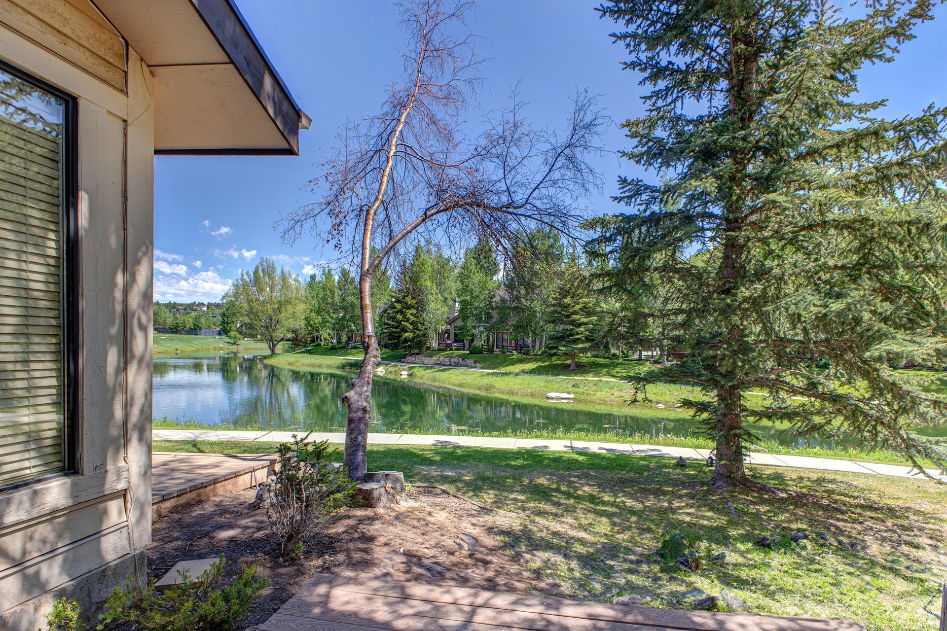 Queen Esther 2425 sits peacefully along a small lake surrounded by trees and greenery.