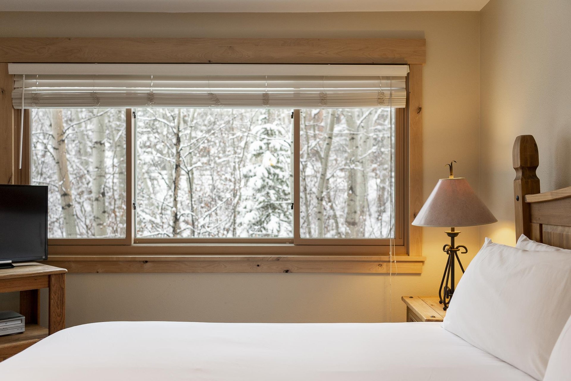 The main bedroom offers a large picture window with views of the forest covered in snow.