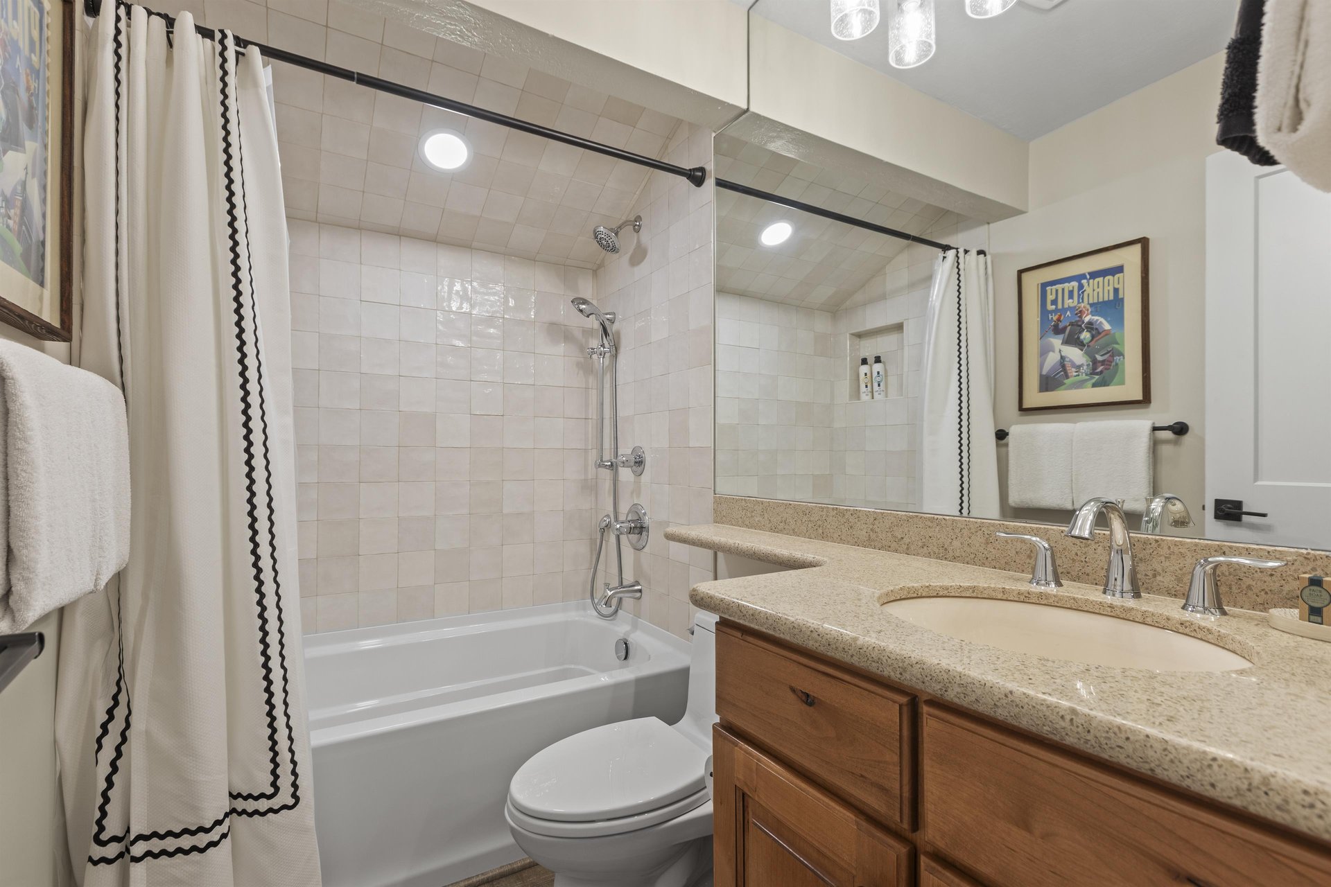 The shared bathroom offers a single sink vanity and bathtub and shower combination.