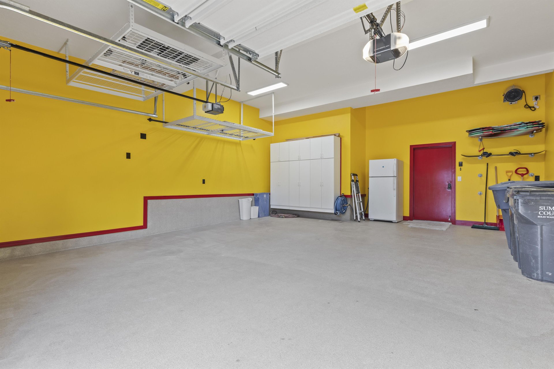 The garage painted yellow with a red door and trim and new floor finish.