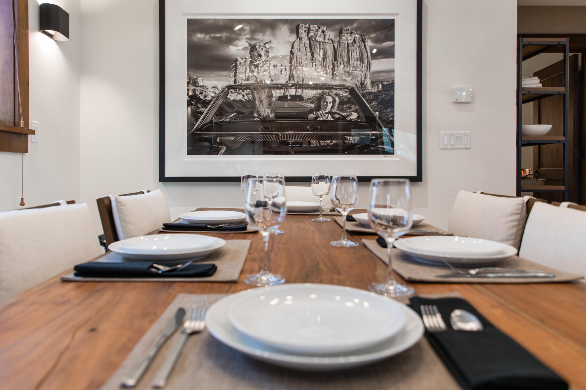 The dining table has seating for 6 guests and black and white artwork.