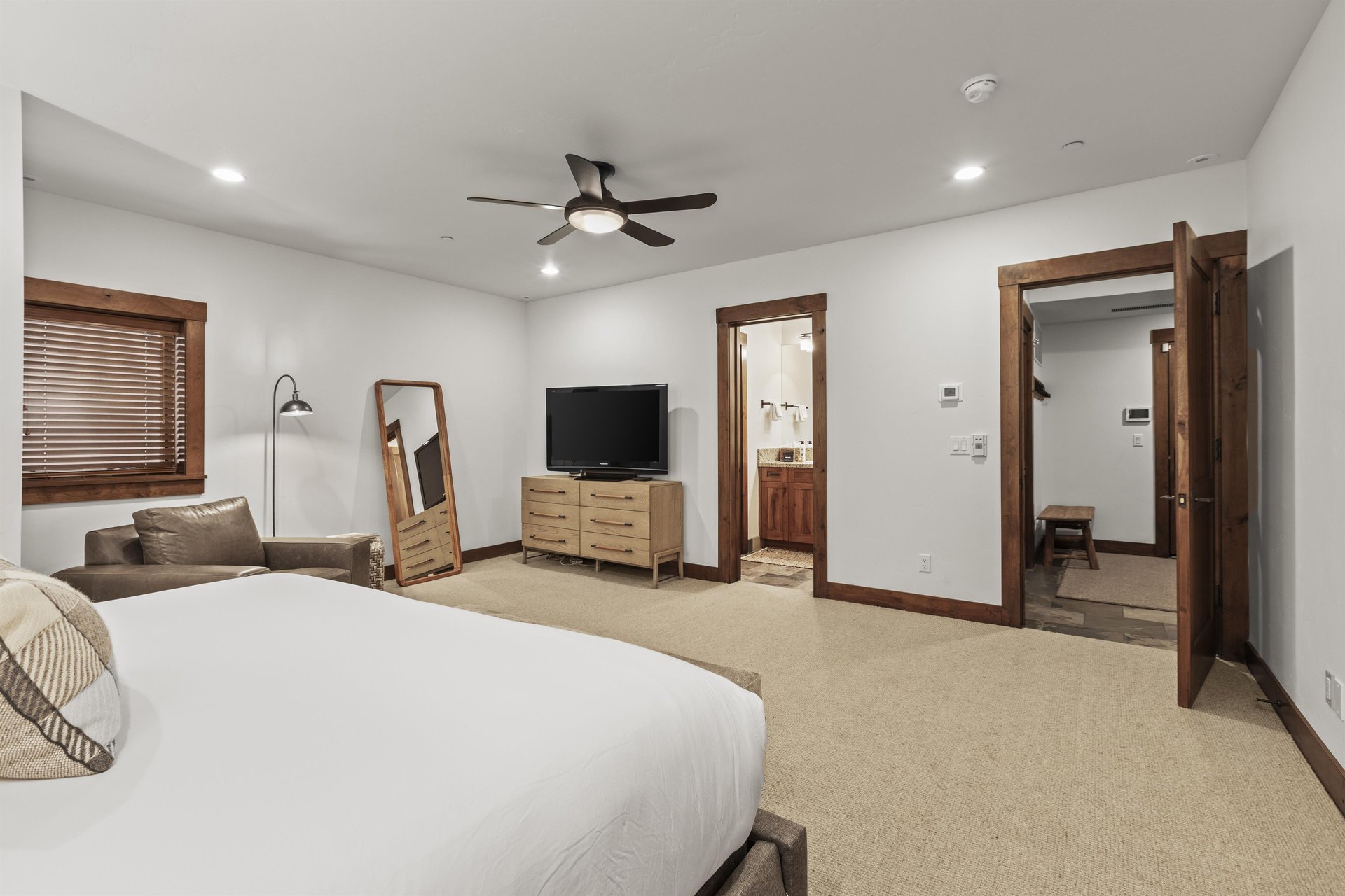 The spacious main suite has a floor mirror, dresser, and flat screen TV.