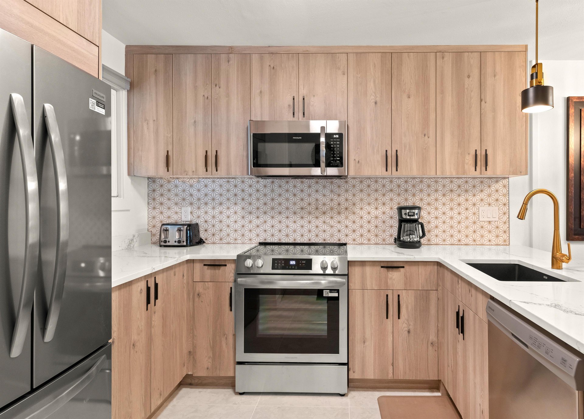 The beautiful kitchen has stainless steel appliances, warm wood cabinets, and white accents.