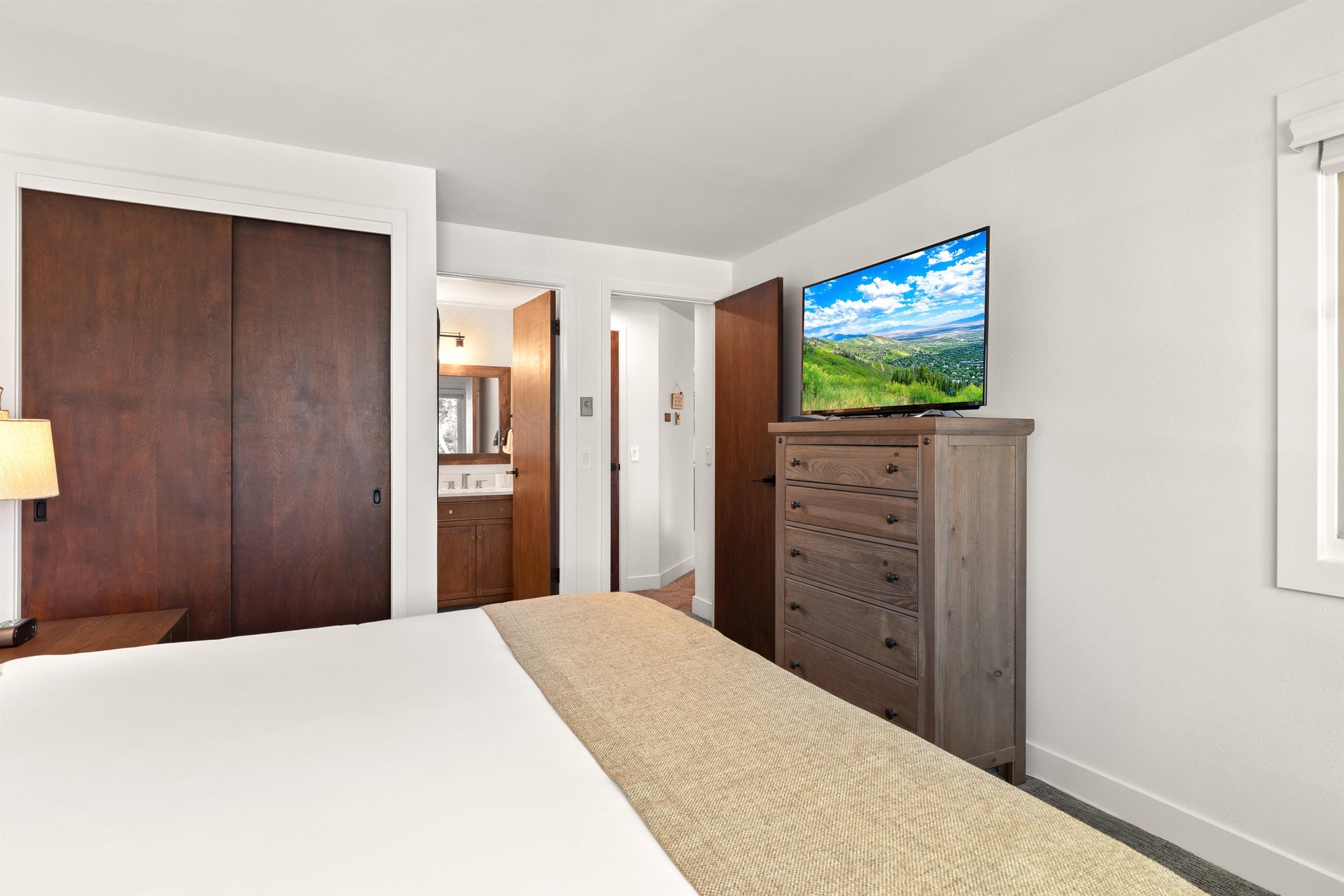 The main suite with a king size bed, tall dresser, and flat screen TV.