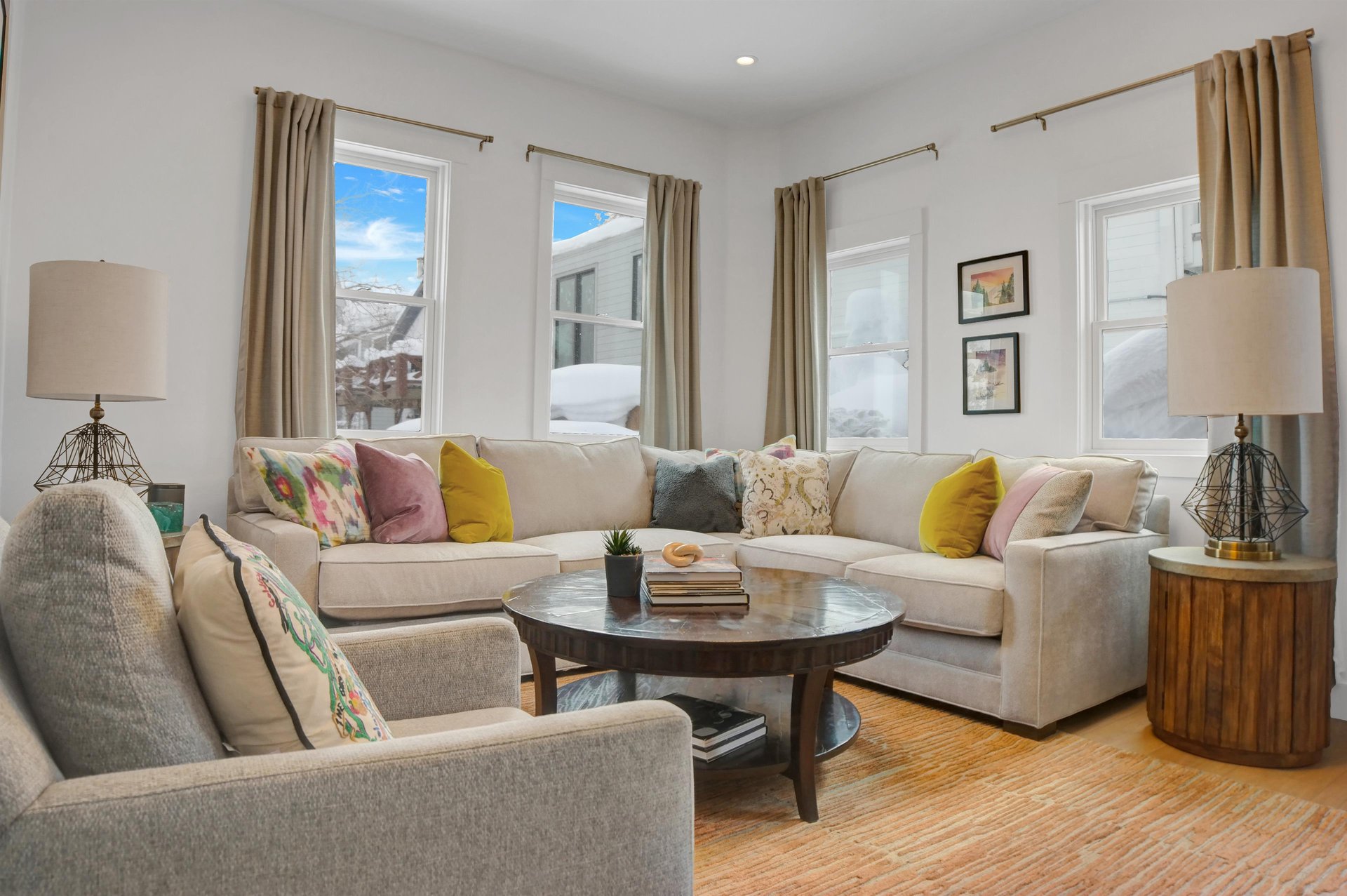 Enjoy the apres room with cream color sectional couch, colorful pillows, white walls, wooden coffee table.