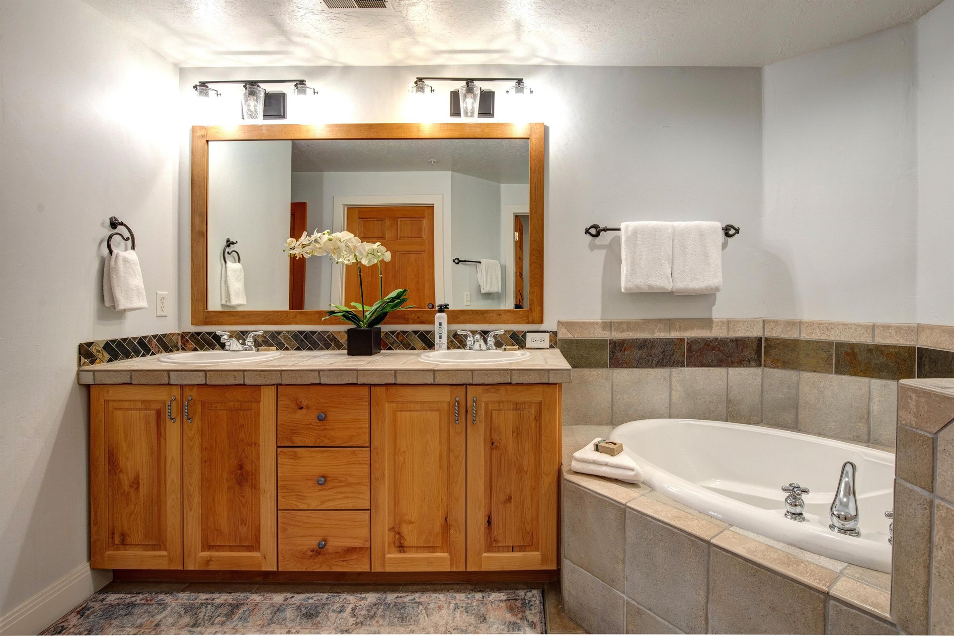 Relax in your spacious bathroom featuring a luxurious soaking tub, elegant vanity with ample storage, and thoughtful amenities.