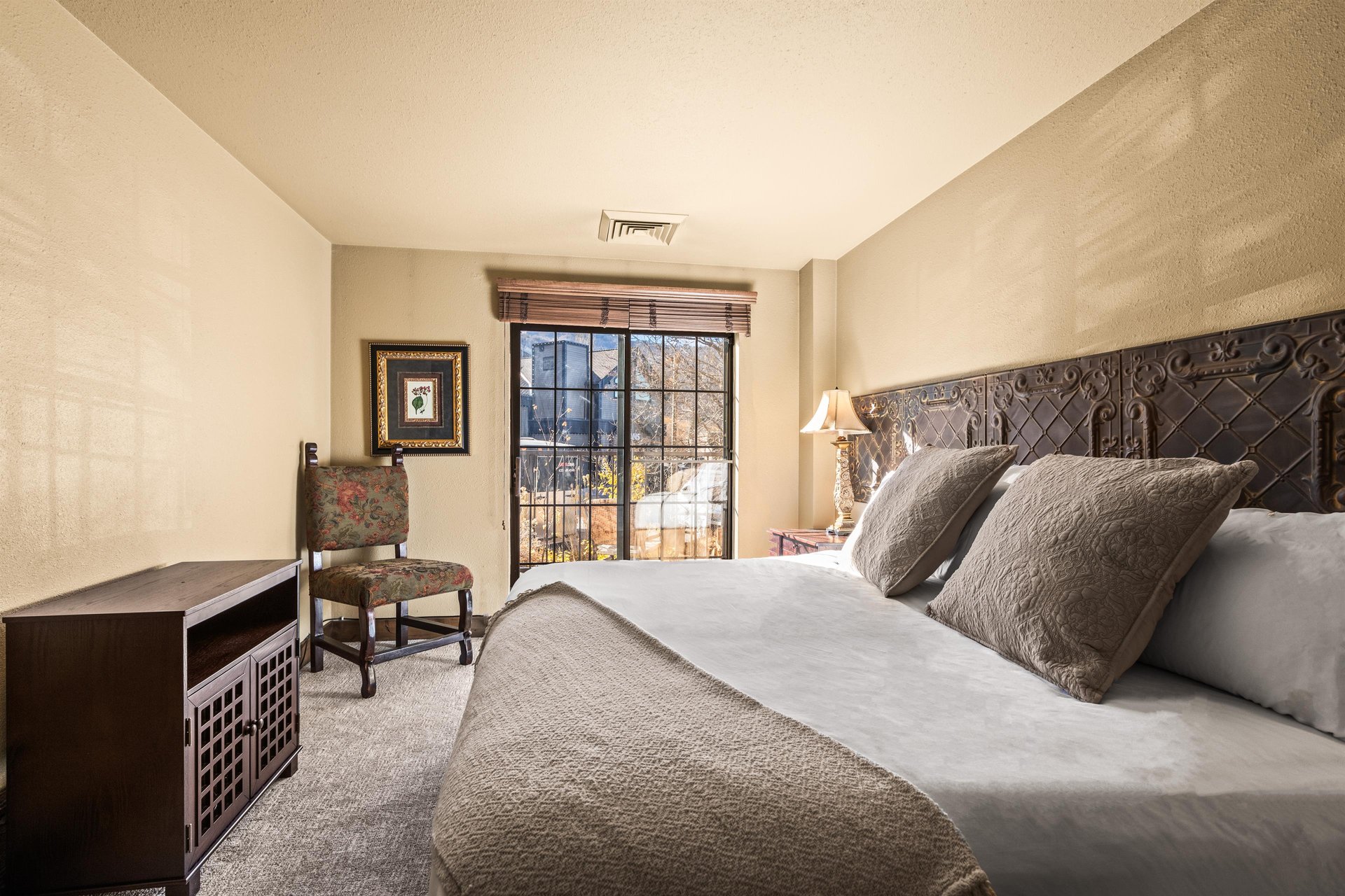 Sink into luxury in your serene bedroom, where an ornate carved headboard and plush linens create the perfect retreat.