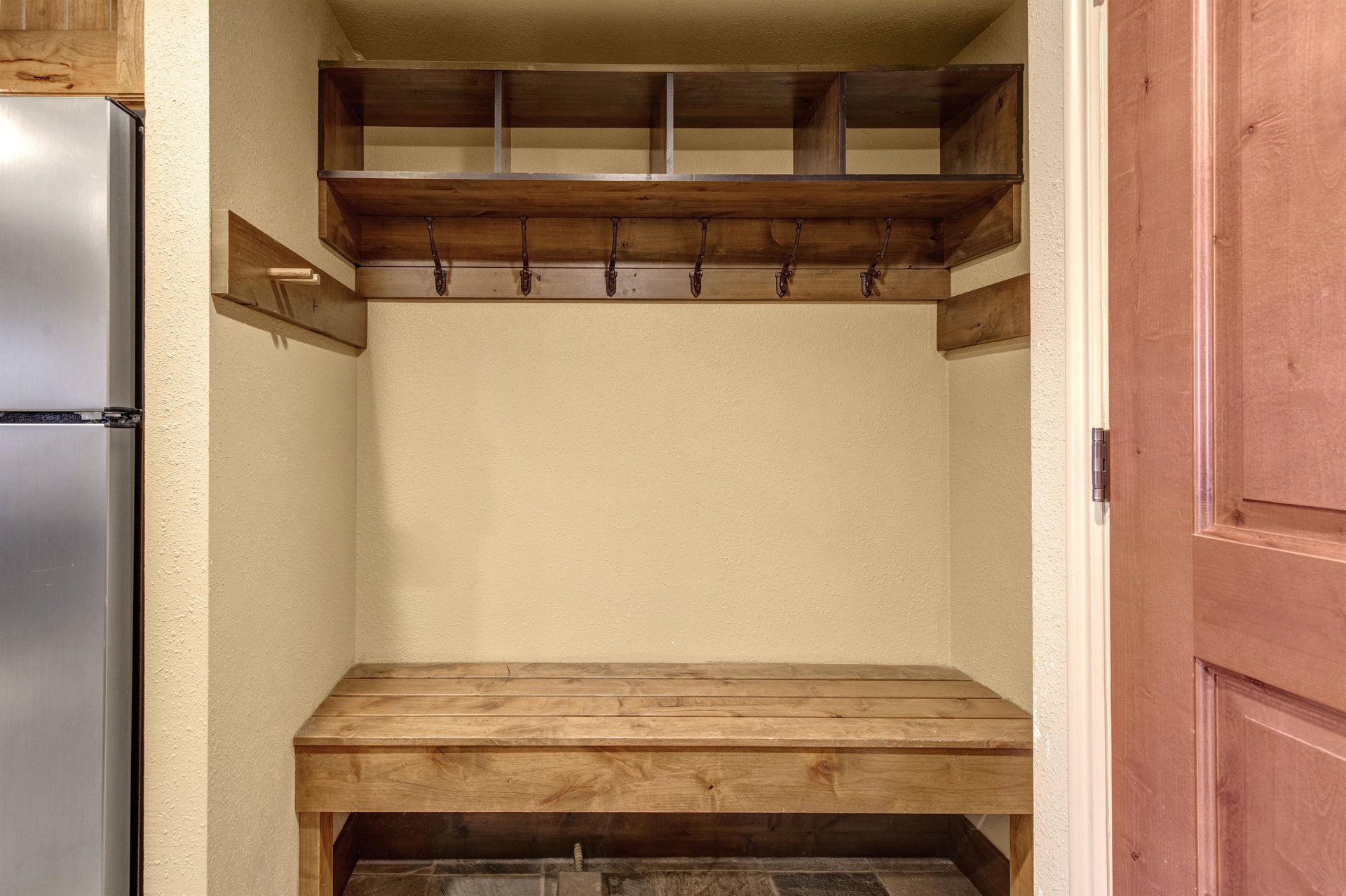 Your private mudroom awaits with custom wooden storage cubbies and hooks to keep your gear organized.