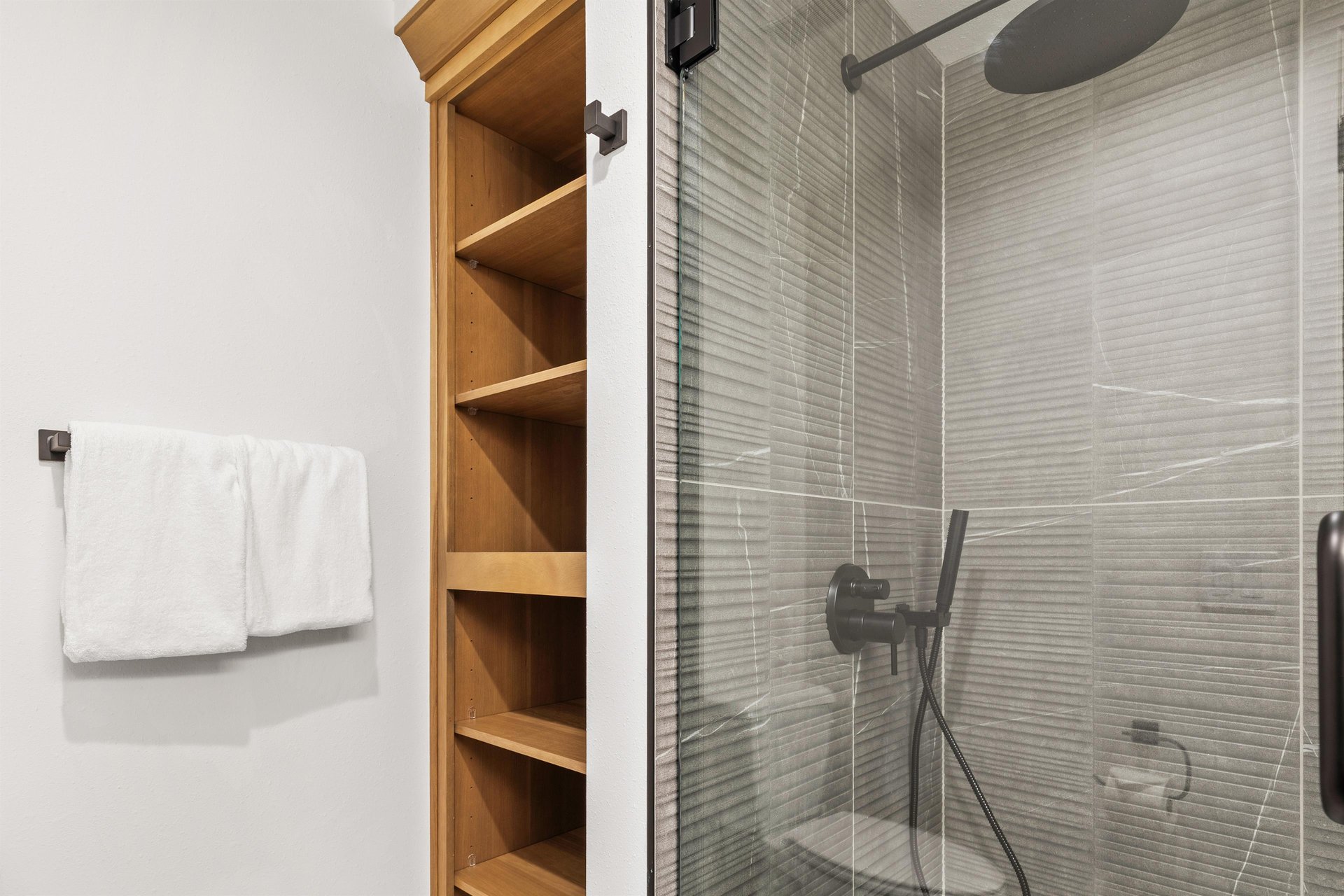 Step into your modern ensuite featuring a sleek glass shower with contemporary fixtures and convenient builtin storage for your essentials.