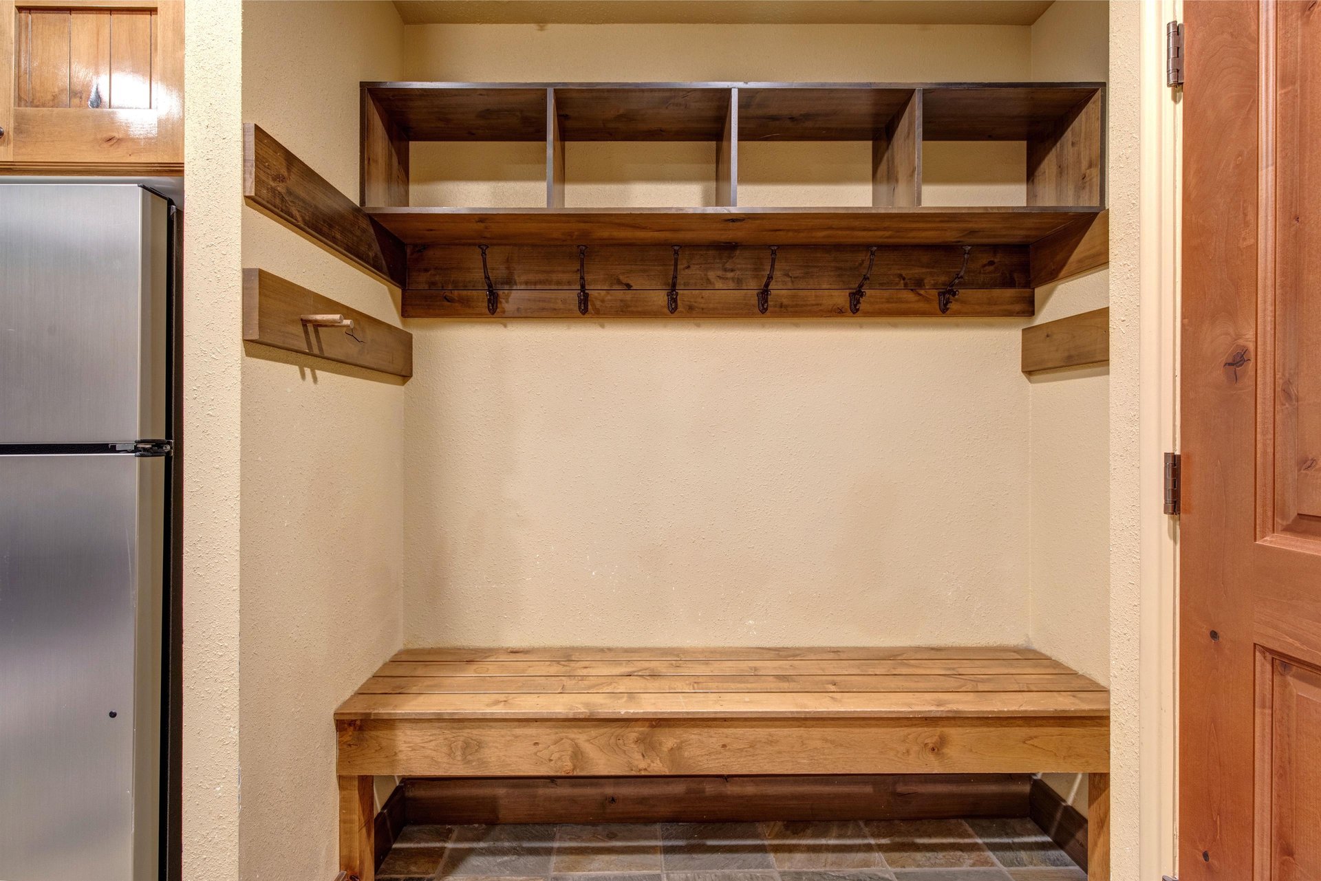 Your own organized mudroom awaits with custom wooden storage cubbies and hooks for your gear.