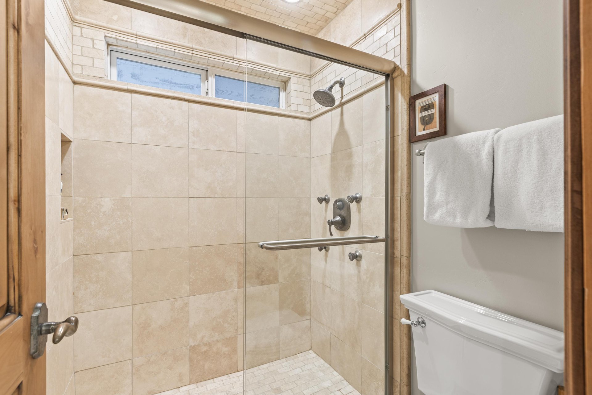 Step into your private spalike retreat with travertine tiles, rainfall showerhead, and fluffy towels.
