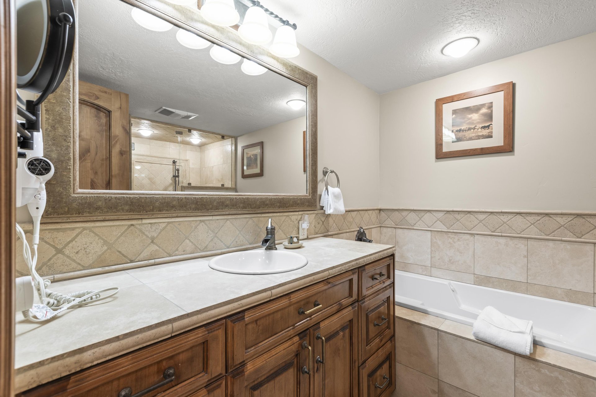 Unwind in your private bathroom featuring warm wood vanity and soaking tub.