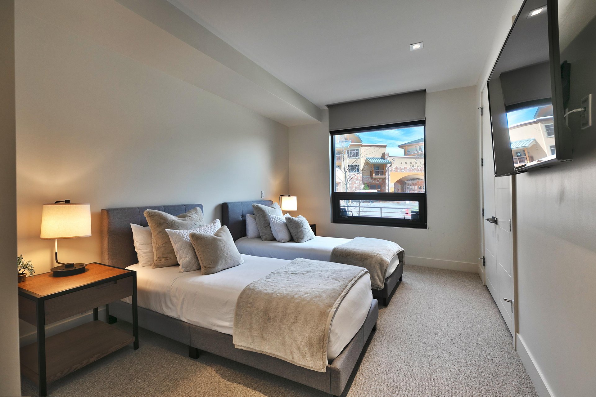 Guest bedroom, platform extra long twin beds, white linens with cozy throw pillows and extra blankets, beautiful plaza views from the large window