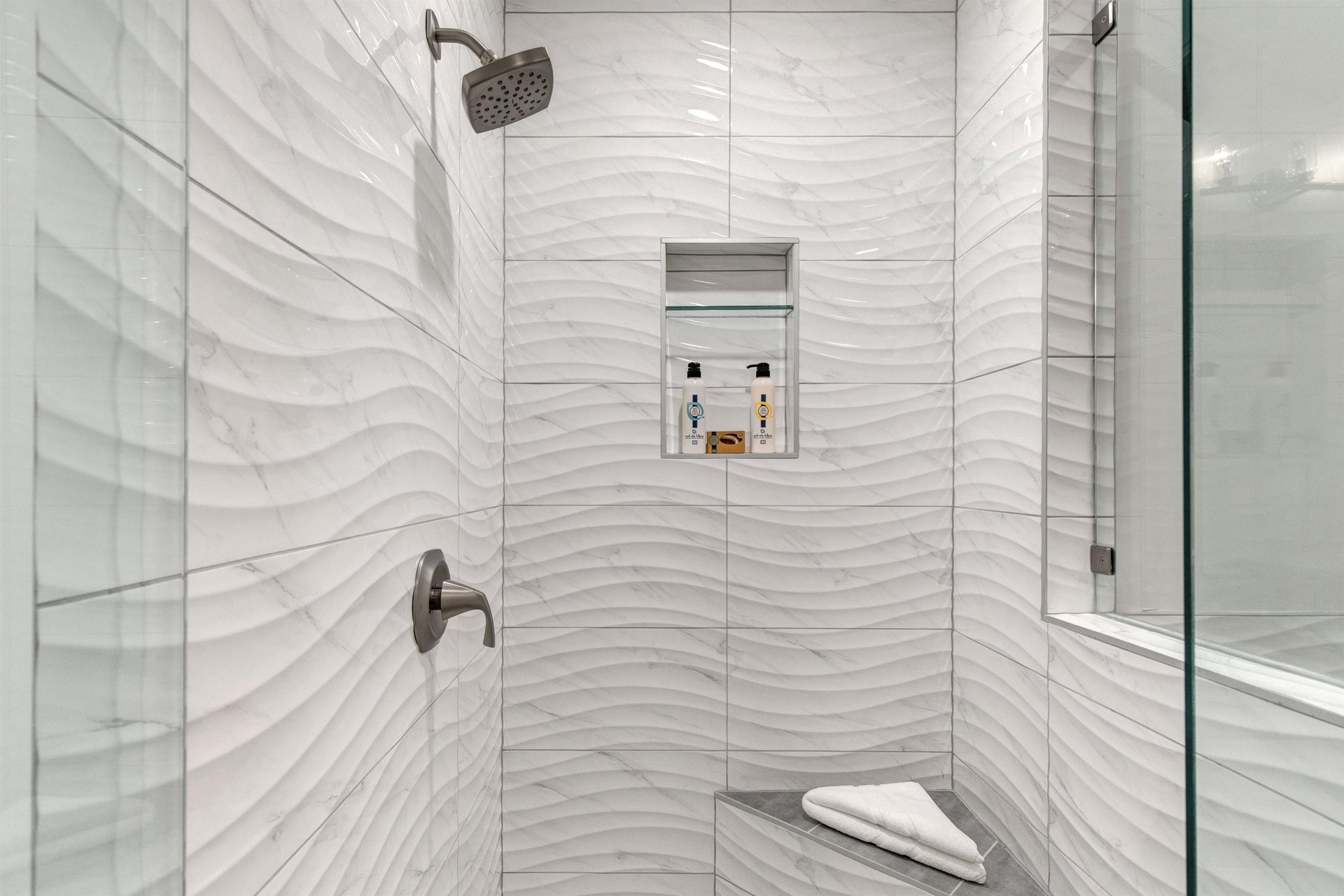 Step into your luxurious walkin shower with stunning wavetextured tiles and rainfall showerhead.