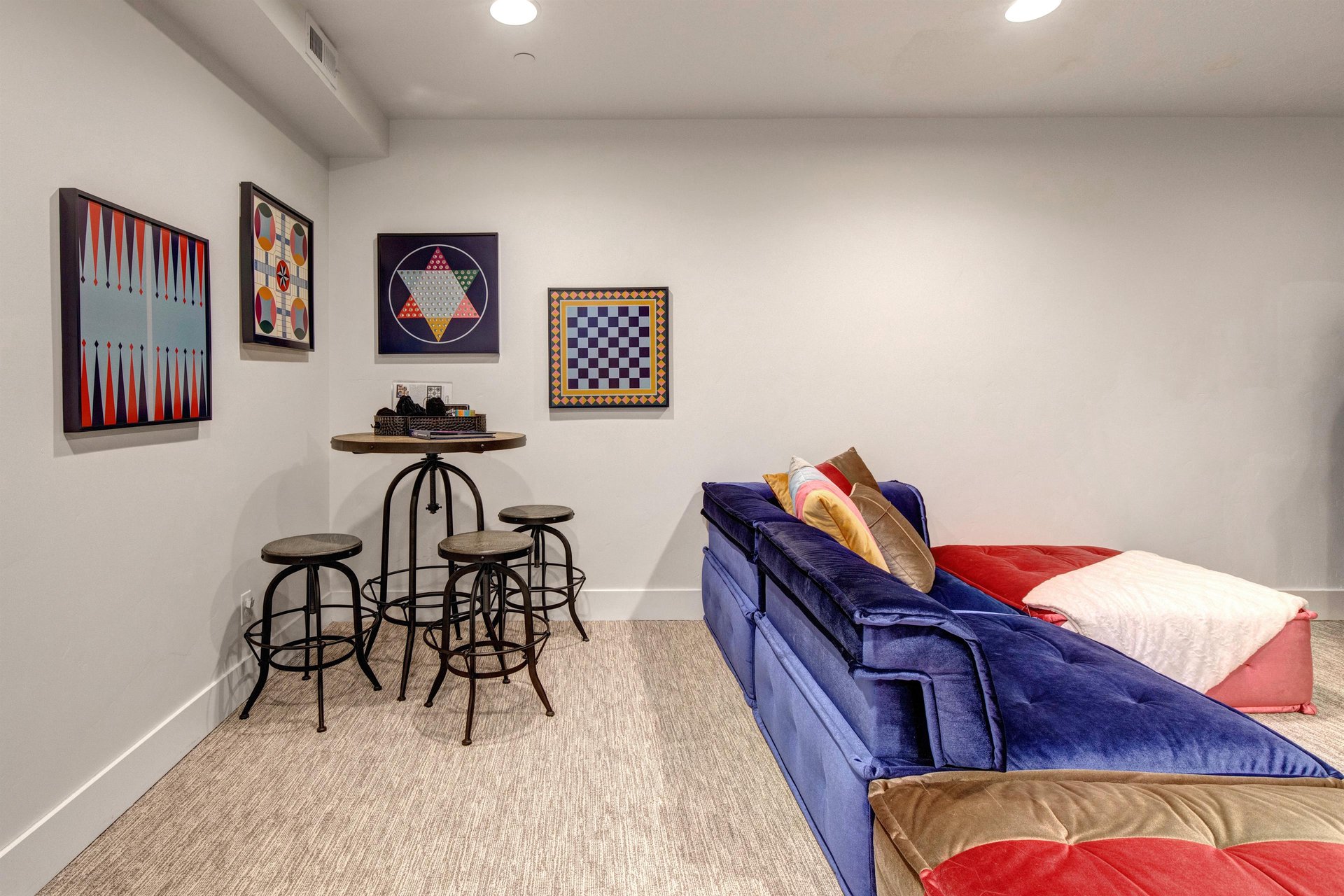 The game room features a plush velvet sofa, fun board games, and colorful wall art.