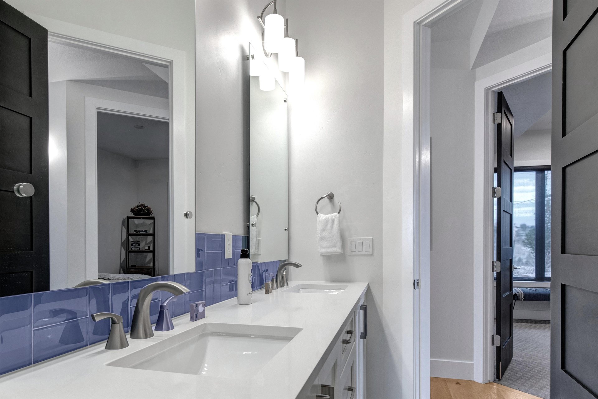 Fresh white towels await you in this sleek bathroom with dual sinks and modern touches.