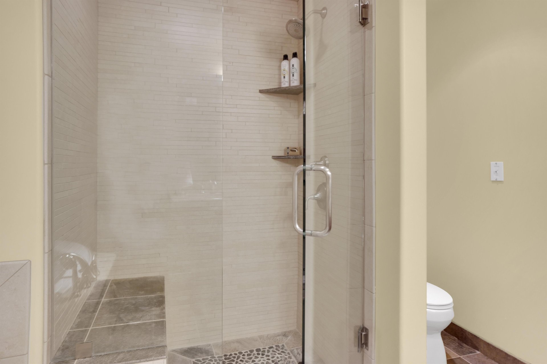 Walkin shower with tile surround, tile sitting bench, and glass enclosure.