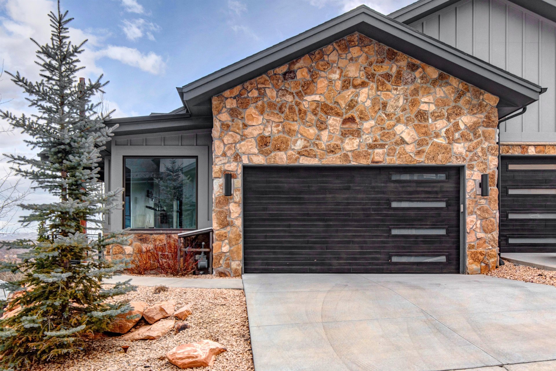 Modern mountain retreat featuring natural stone accents and and two car garage.