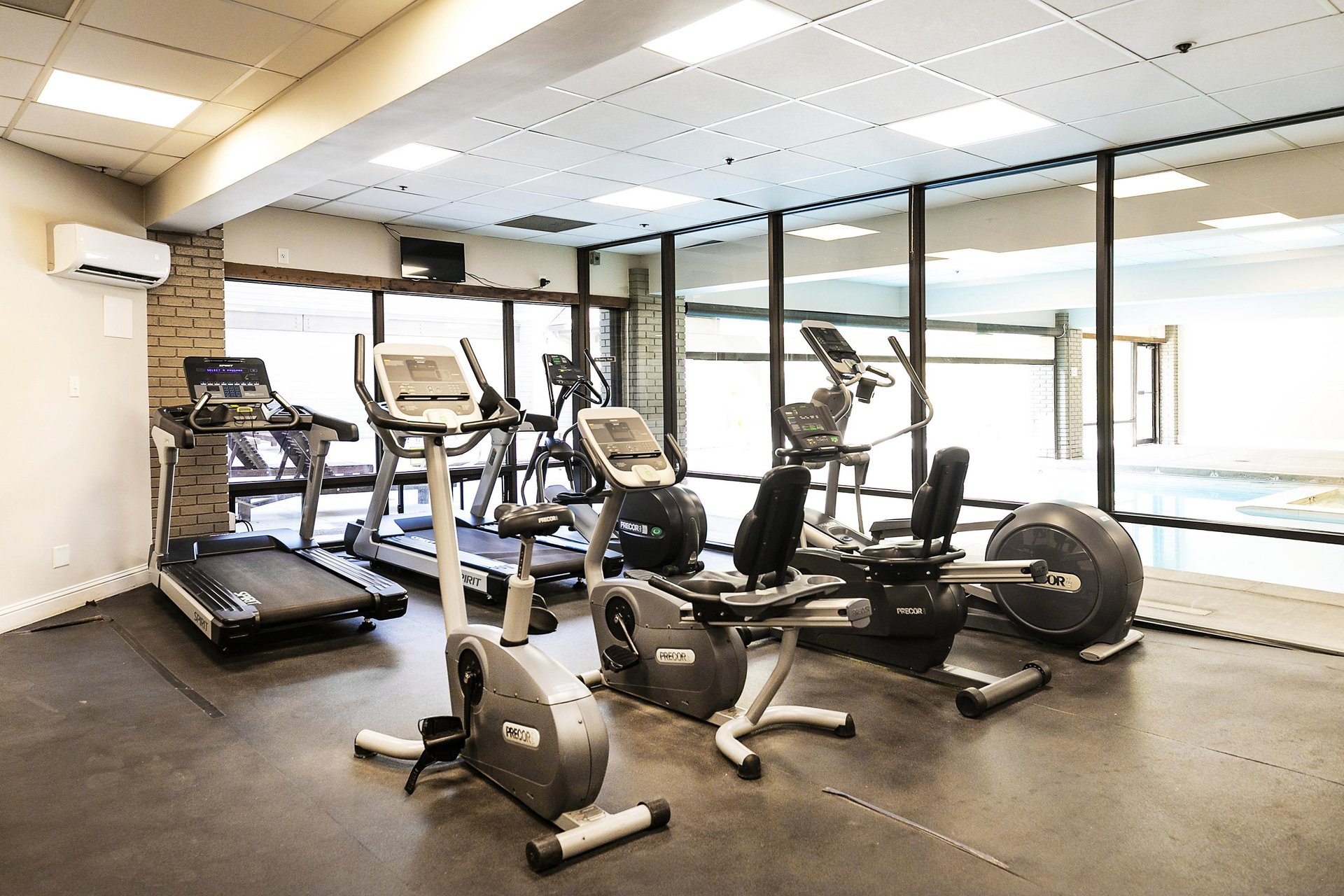 Resort Plazas fitness center with floor to ceiling window walls overlooking the pool and various workout machines.