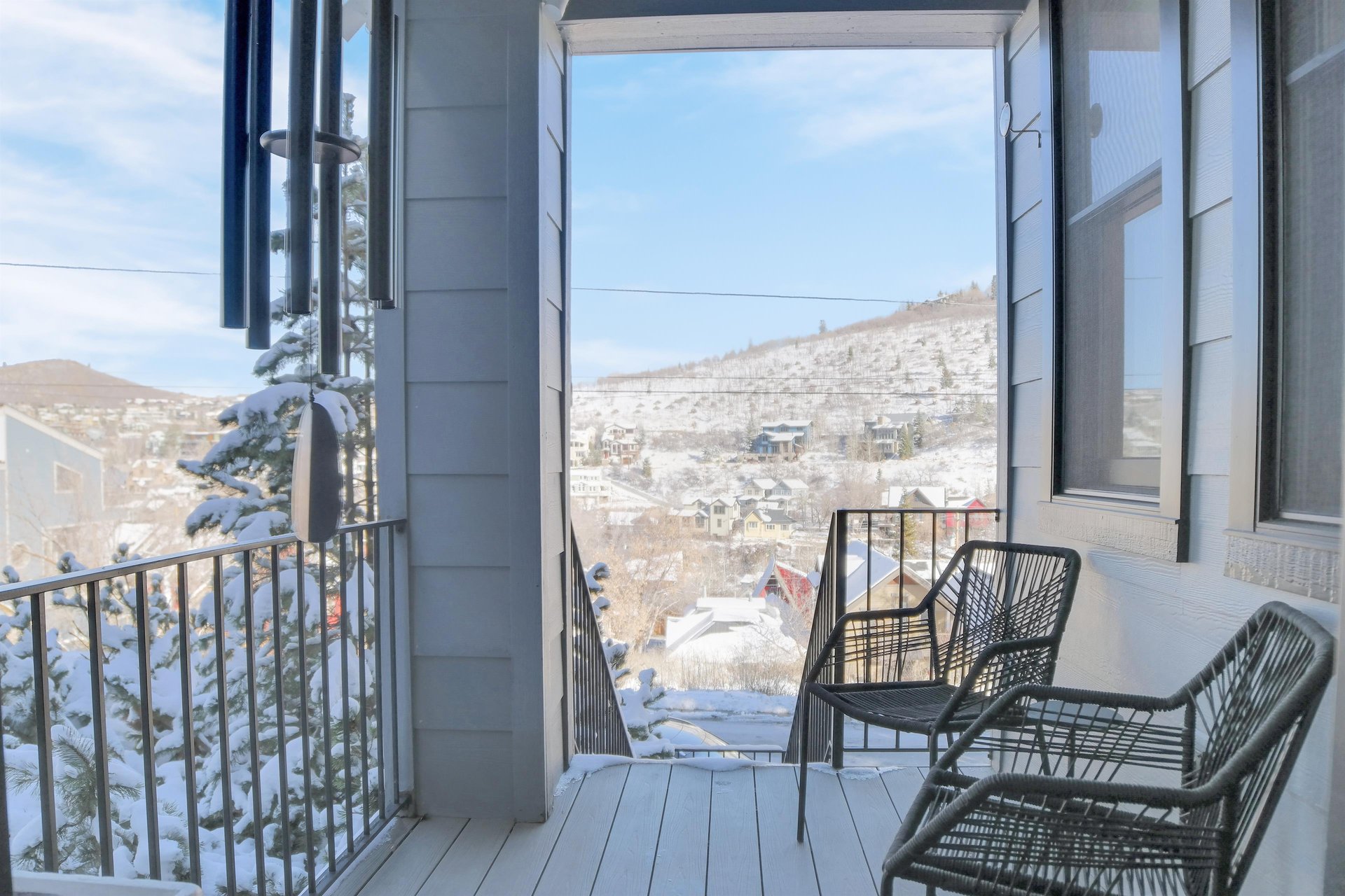 The exterior entryway has two black chairs and overlooks a snowy mountain and Historic Main Street in Park City, Utah.