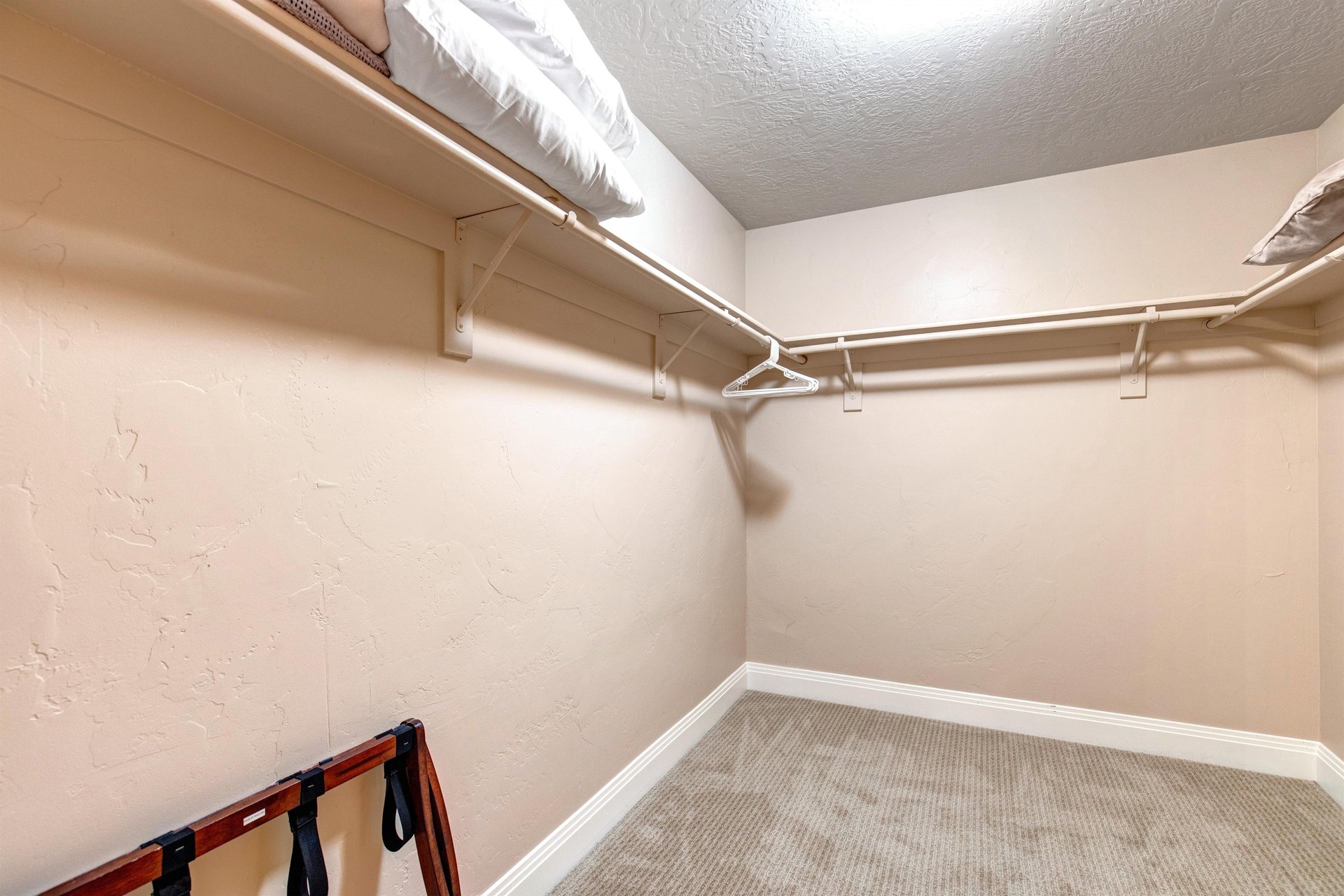 Walkin closet with double hanging rods providing ample space to organize your wardrobe, complete with extra storage on the upper shelf.