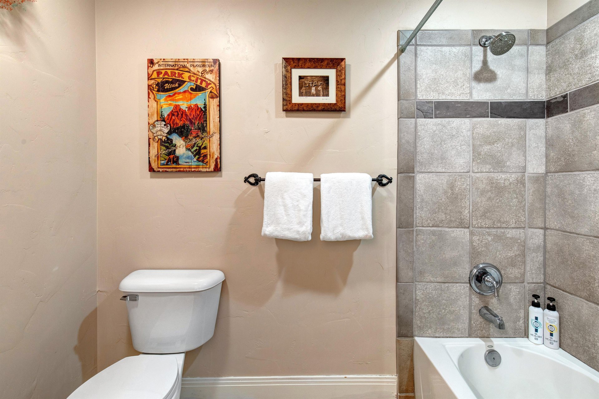 Freshen up in your private bathroom with a modern tiled showertub combo, plush white towels, and thoughtful touches like vintage artwork to make your stay feel special.
