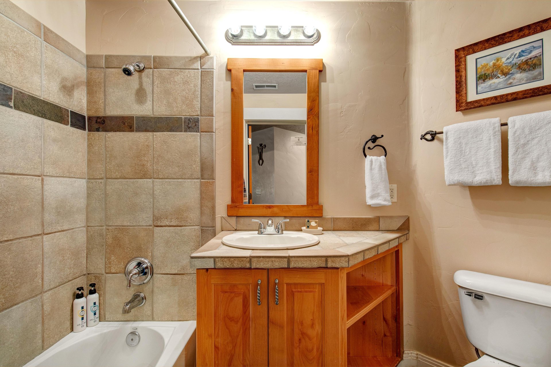 Your private bathroom features warm wood cabinetry, fresh towels, and a tiled tubshower combo—everything you need to unwind after a day of adventure.