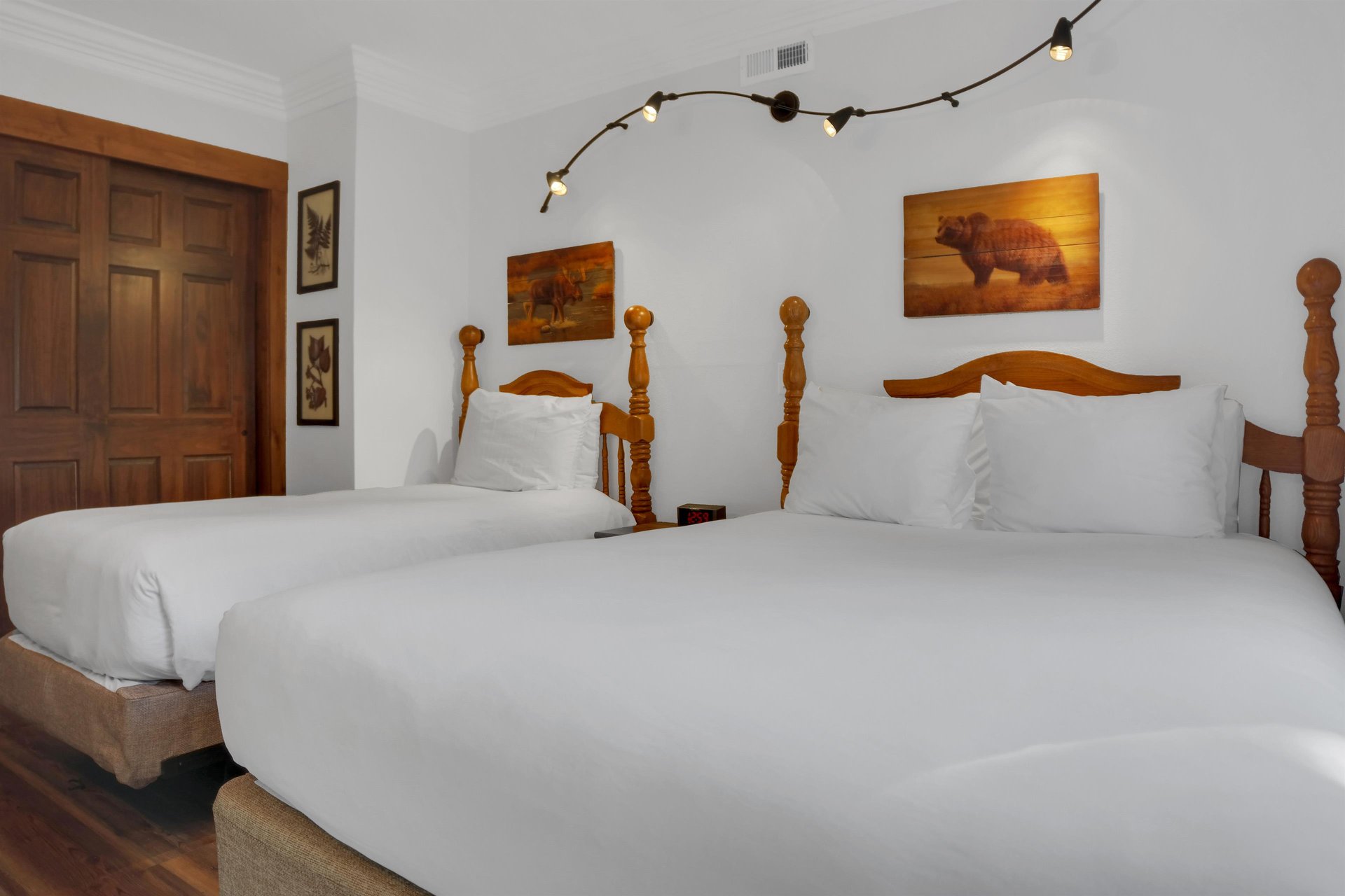The two twin beds have crisp white linens, wood bedframes, and stylish art and lighting above the beds.